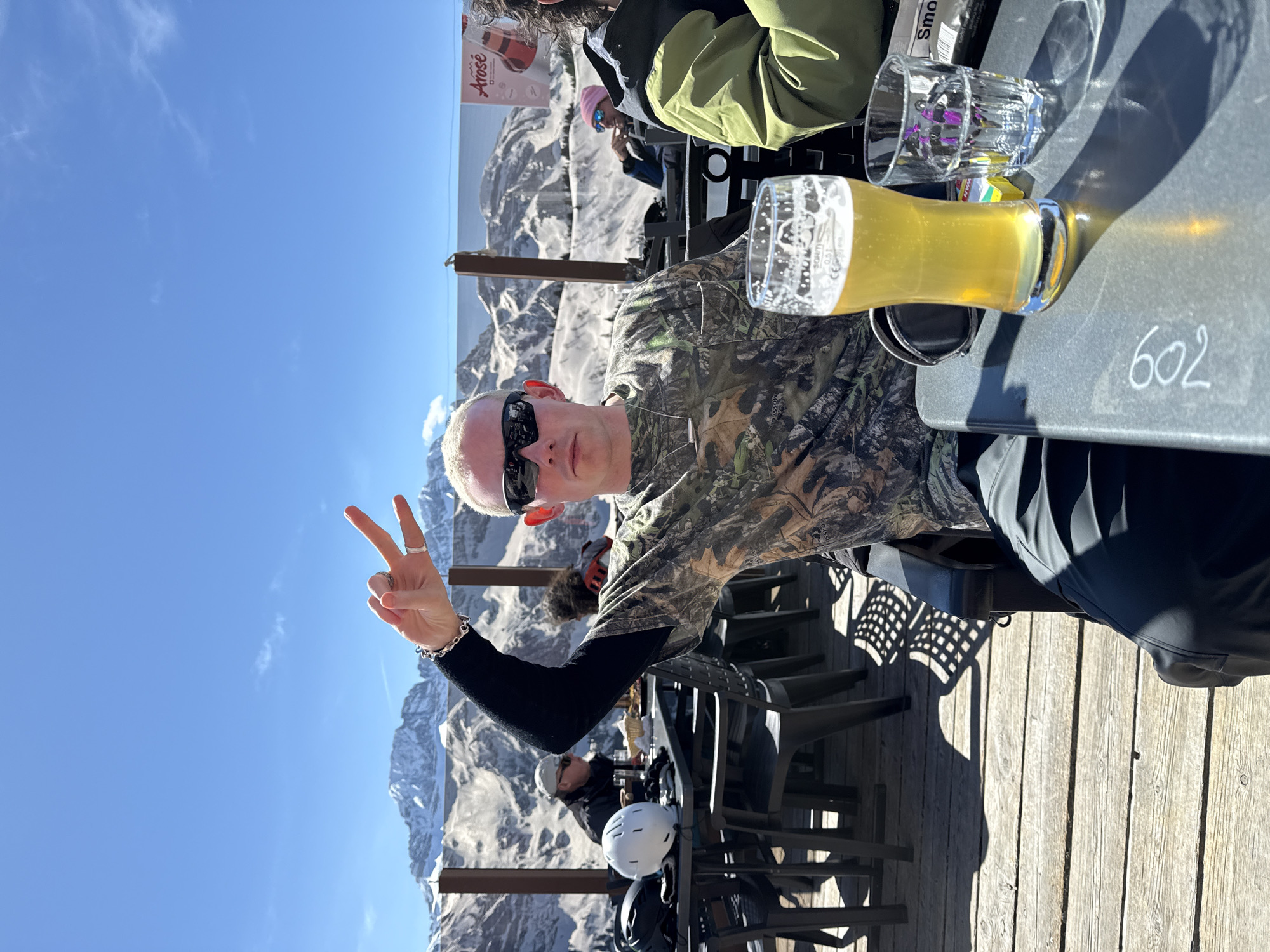 Man makes peace sign at outdoor table in Champéry