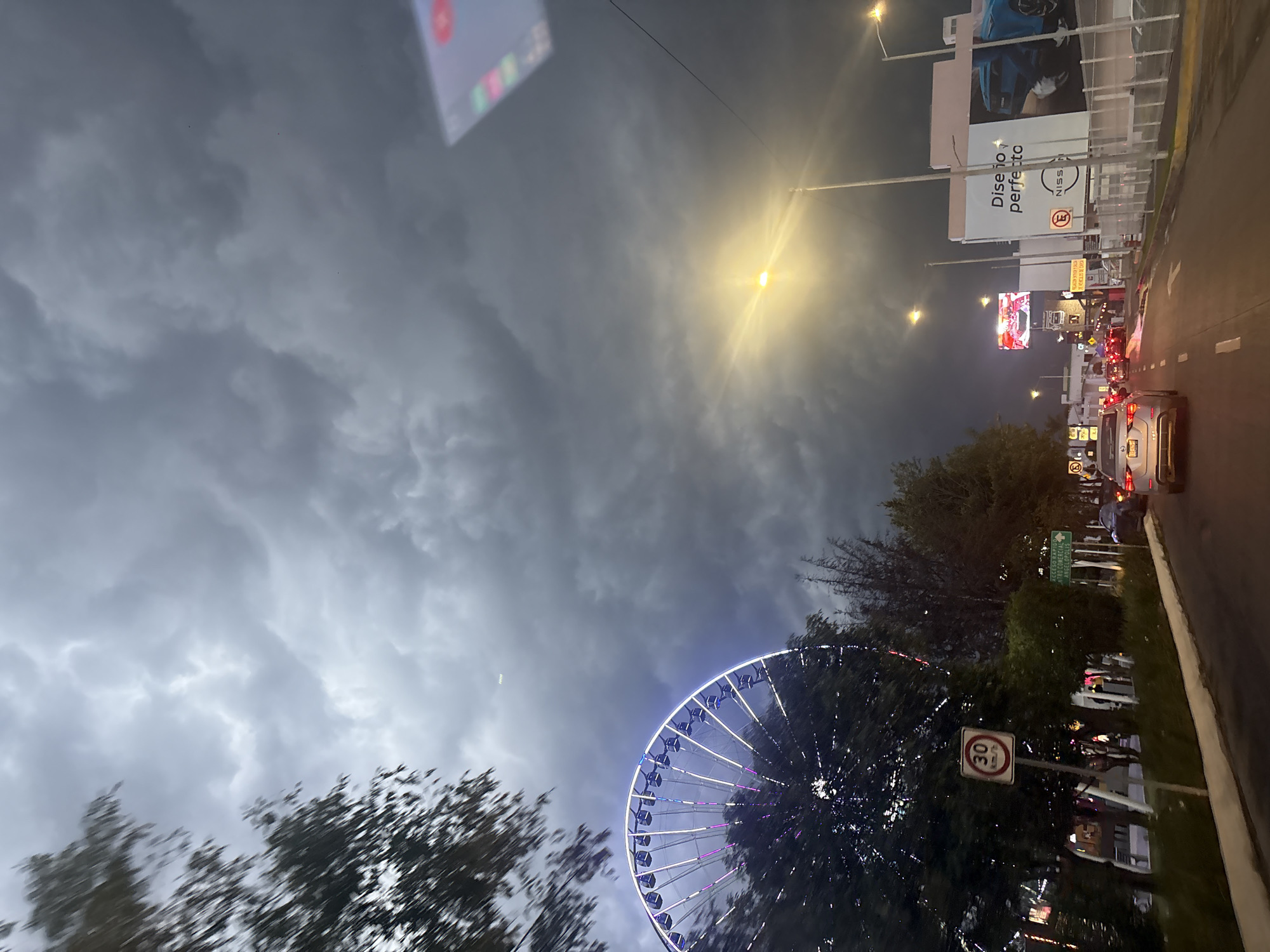 Estrella de Puebla Ferris wheel illuminated purple against cloudy evening