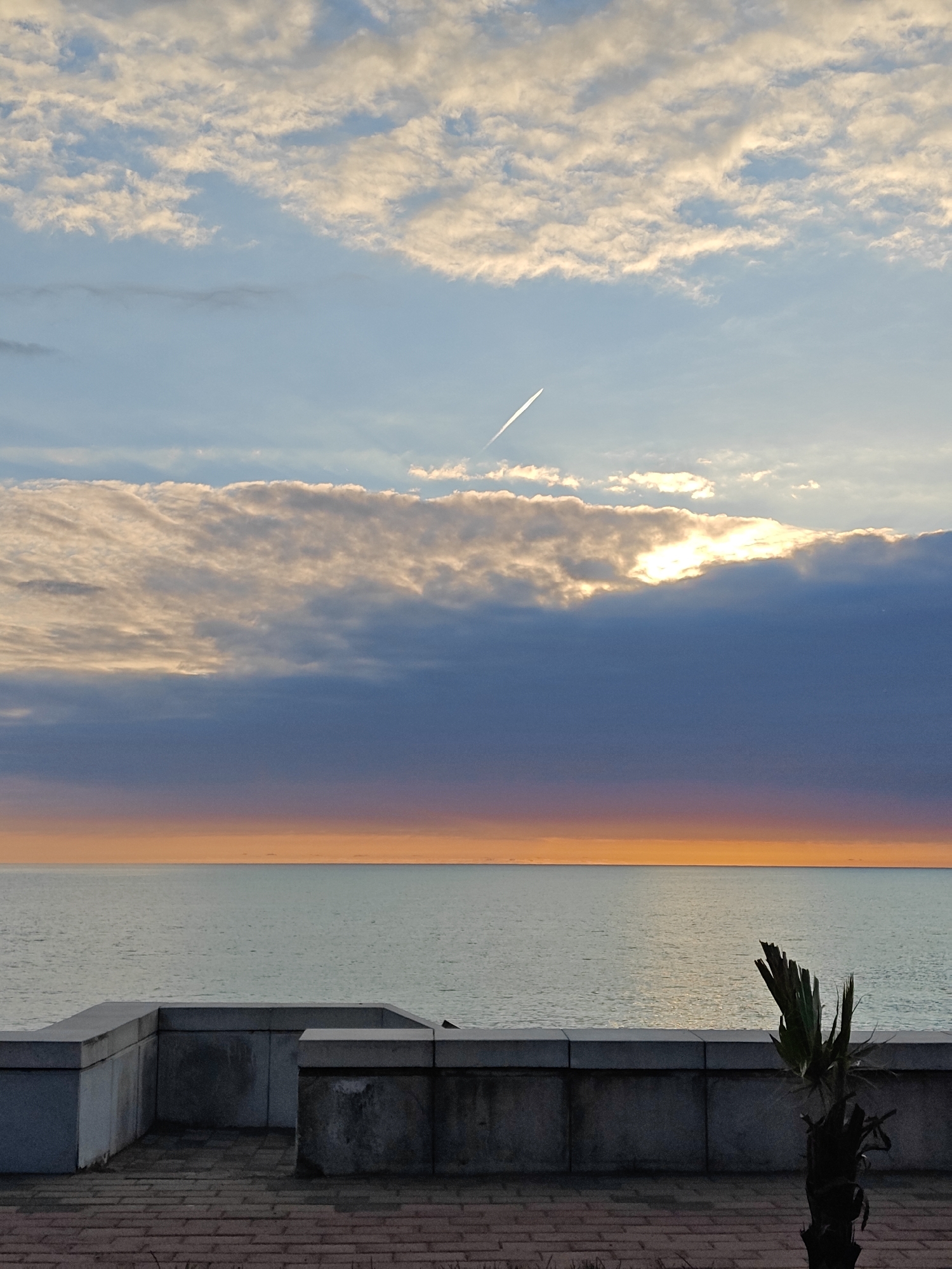 Coastal sunrise/sunset scene captured with brick walkway, dramatic clouds