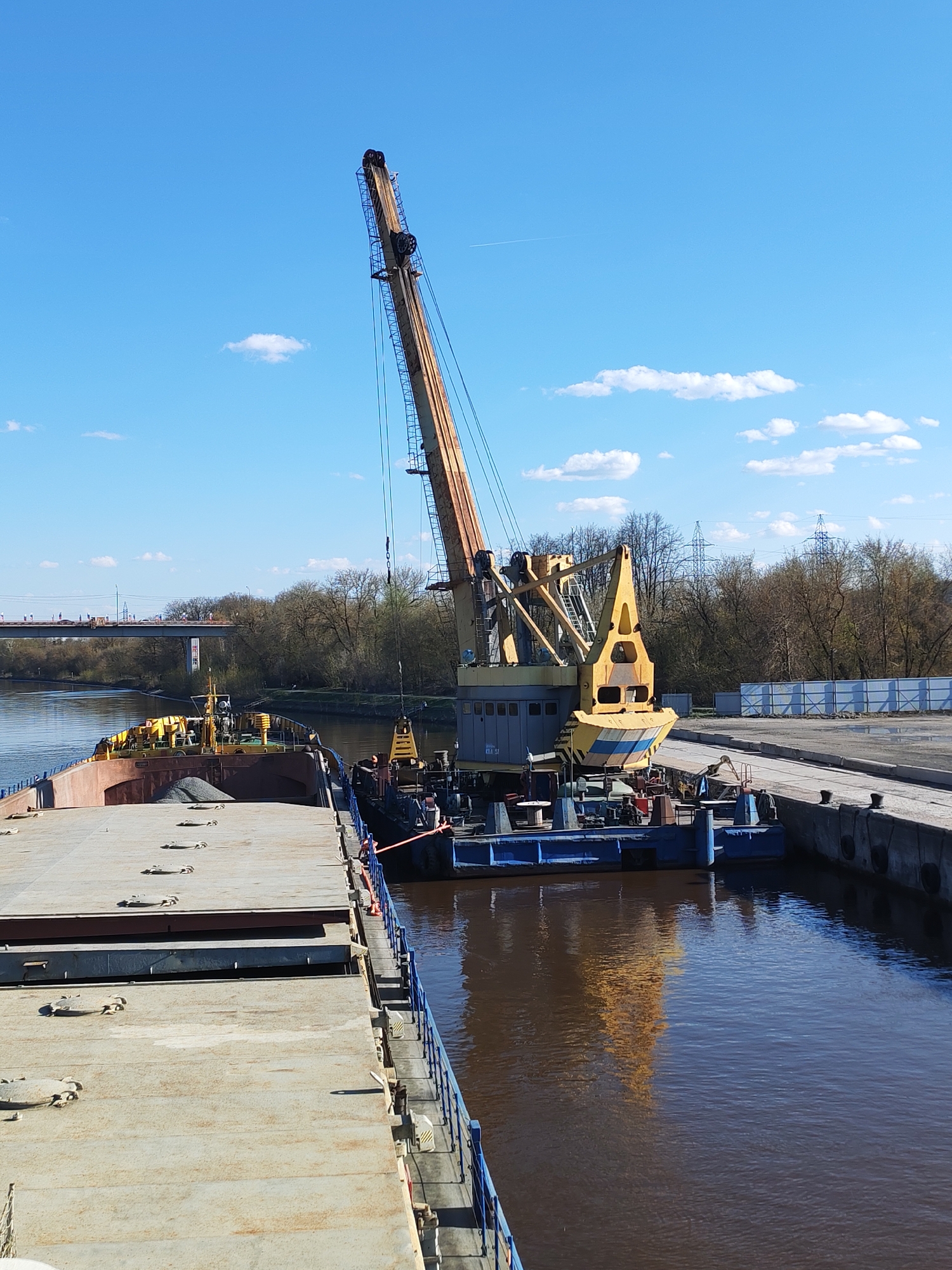 Crane operations transfer gravel between barges on Yakhroma River