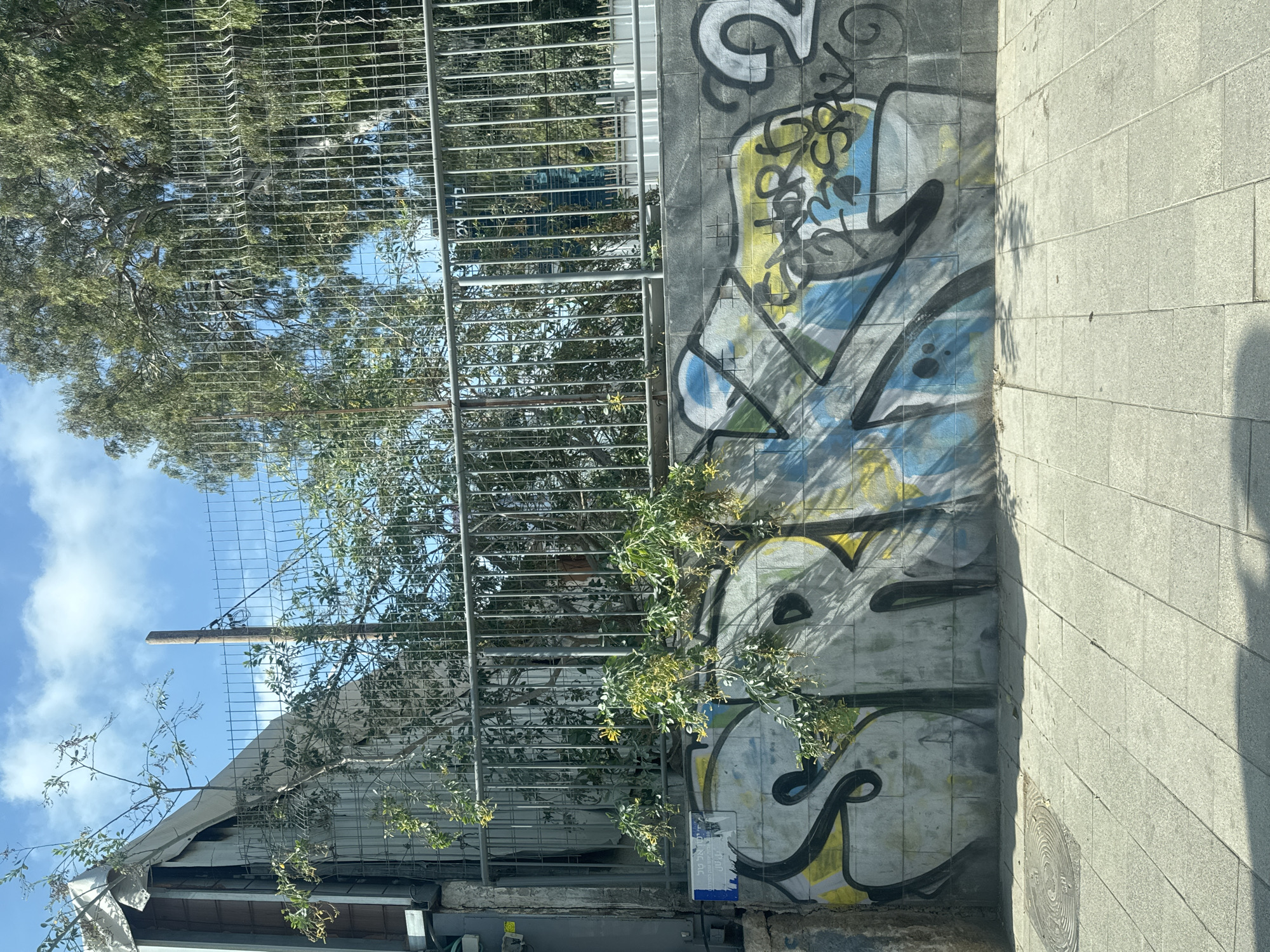 Graffiti wall and shuttered kiosk on a Tel Aviv sidewalk