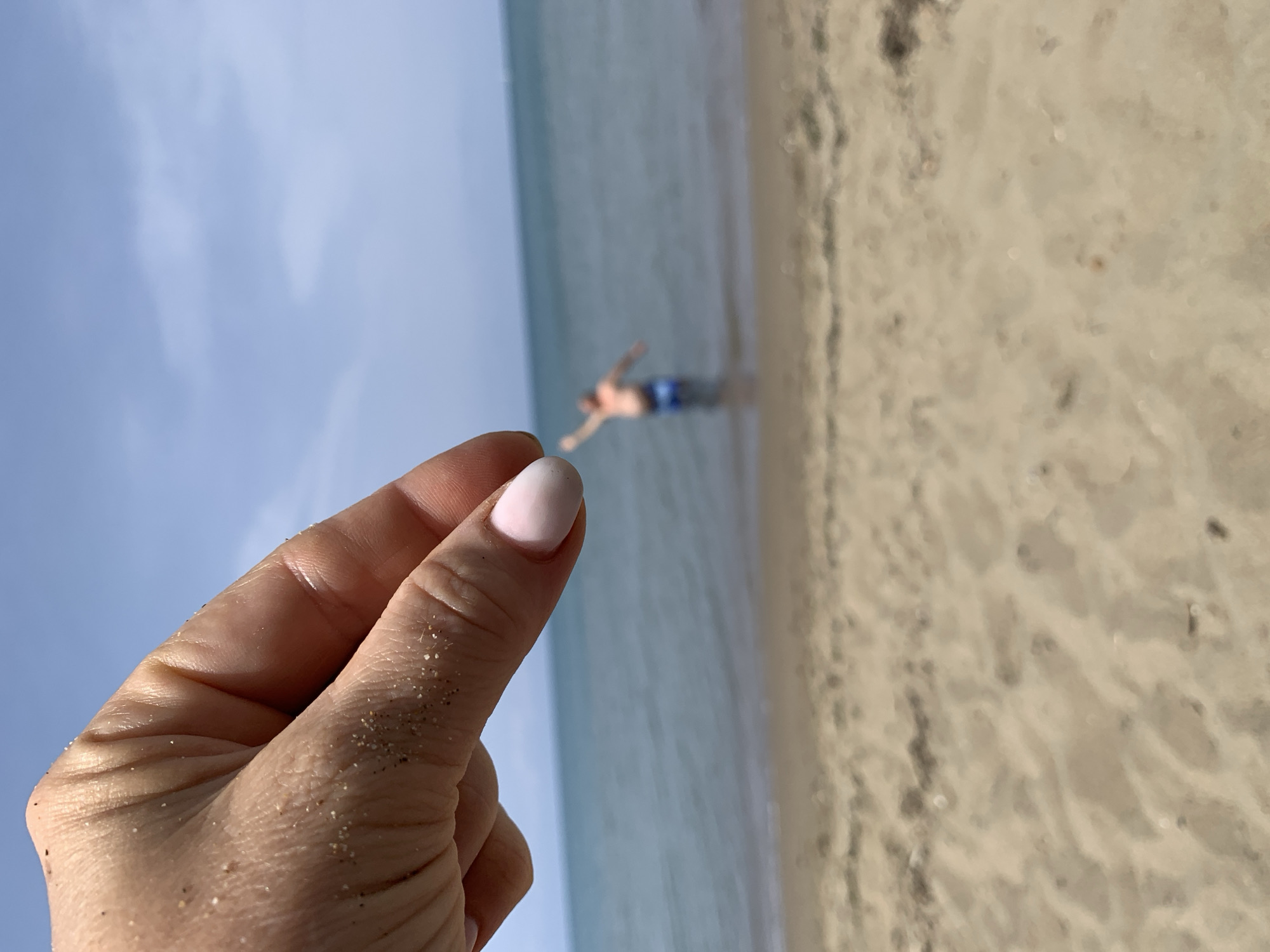 Sand-dusted hand at an Italian beach, summer detail