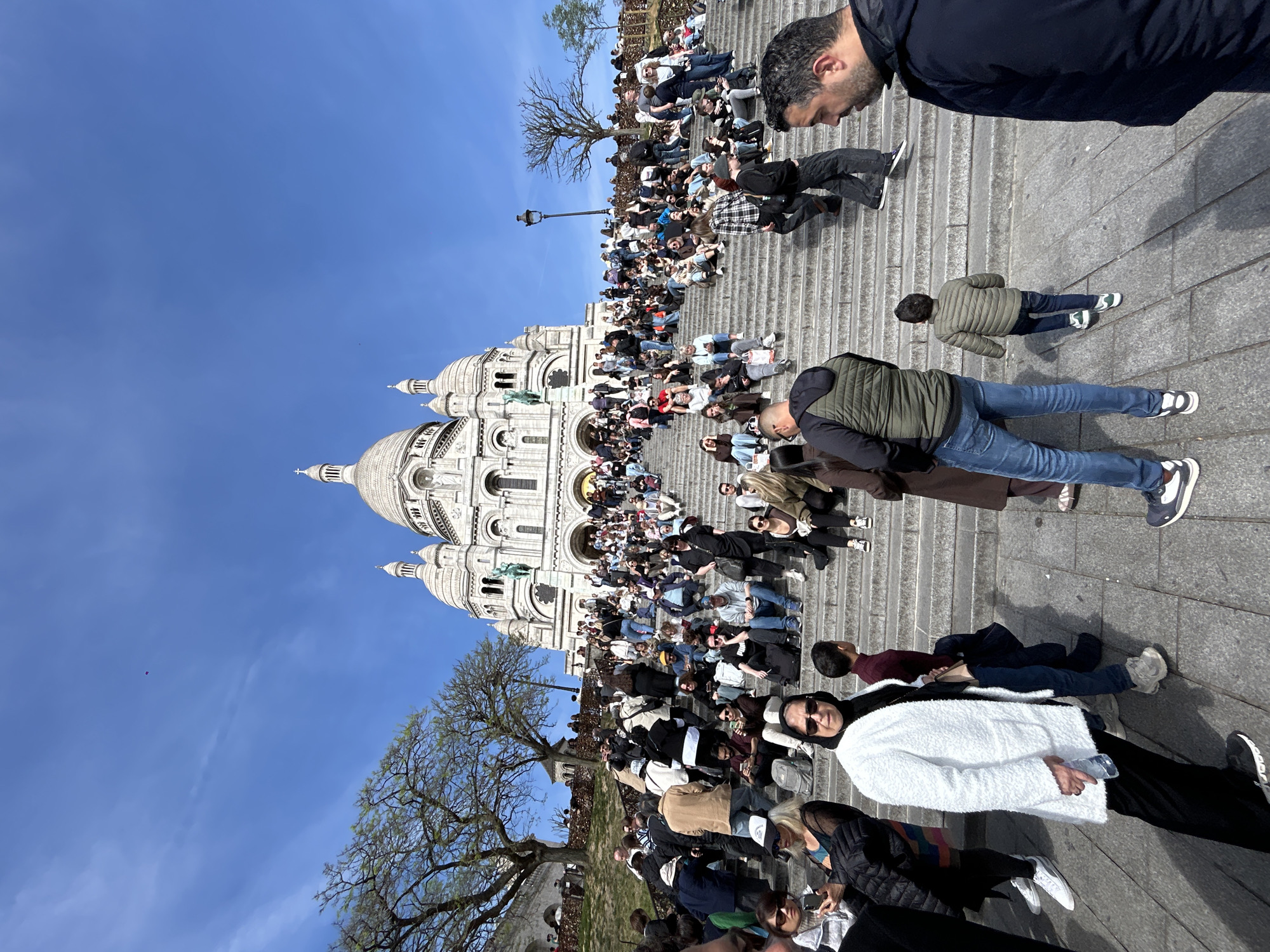 Tourists gather at Sacré-Cœur Basilica on bright Paris day