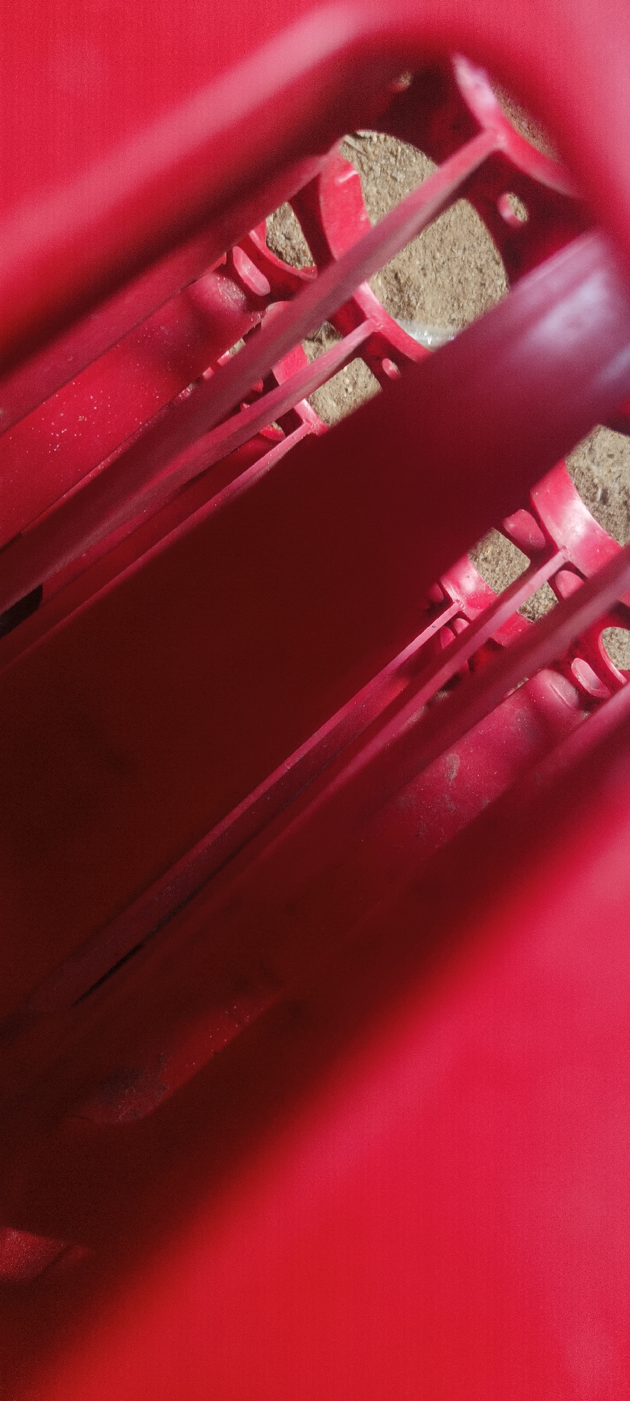 Red plastic crate spotted on sandy ground in Sapele