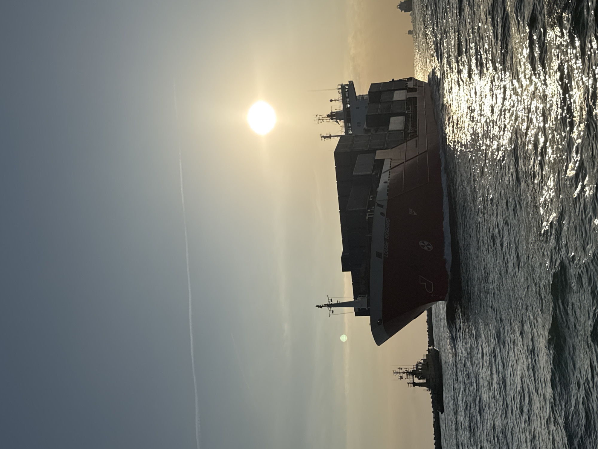Cargo ship and sailboat share the Adriatic at sunrise near Ravenna