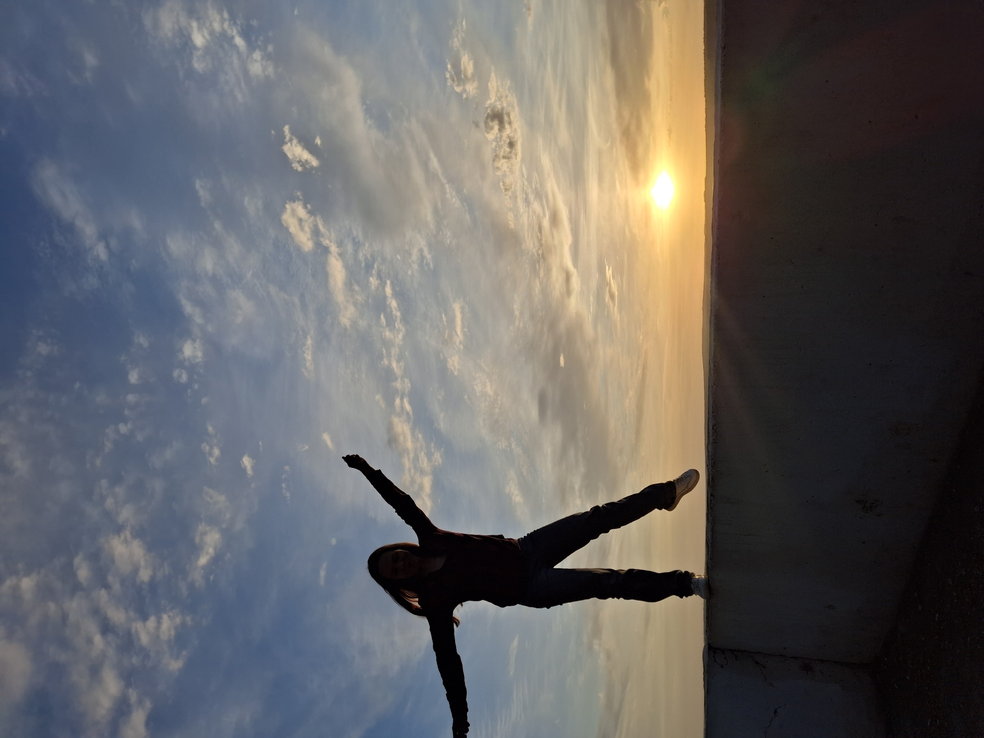 Person photographed balancing on ledge at sunset in Chaikovsky