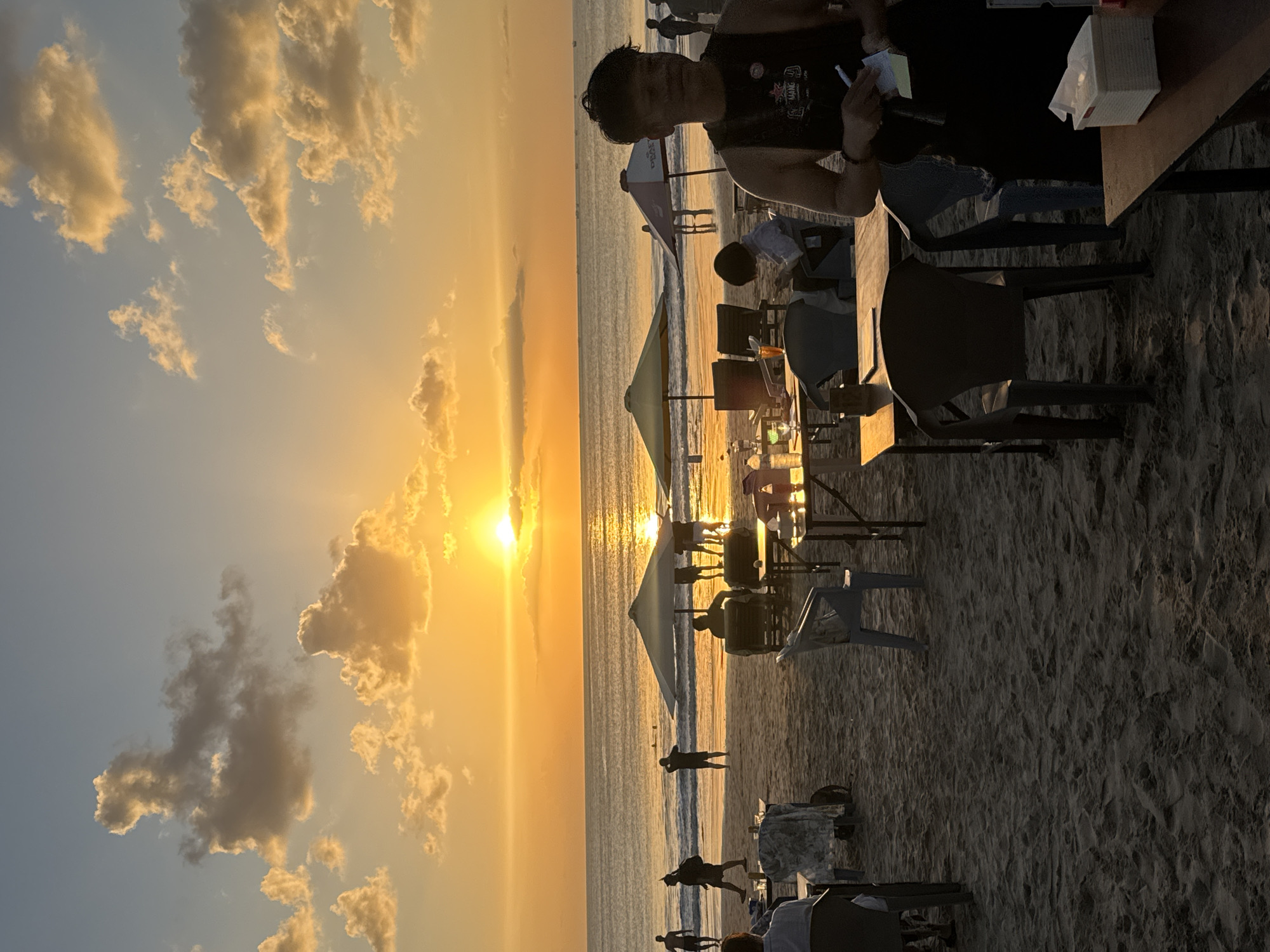 Golden hour on Kuta Beach with planes, waves, and beachgoers