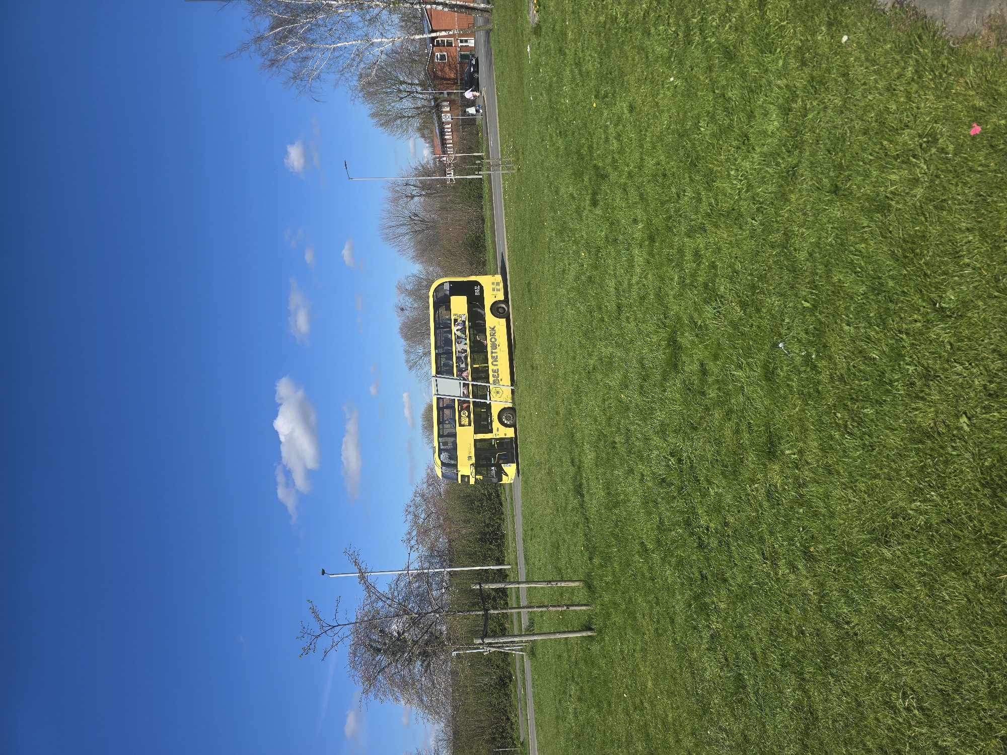 Yellow Bee Network bus travels Manchester road on spring day