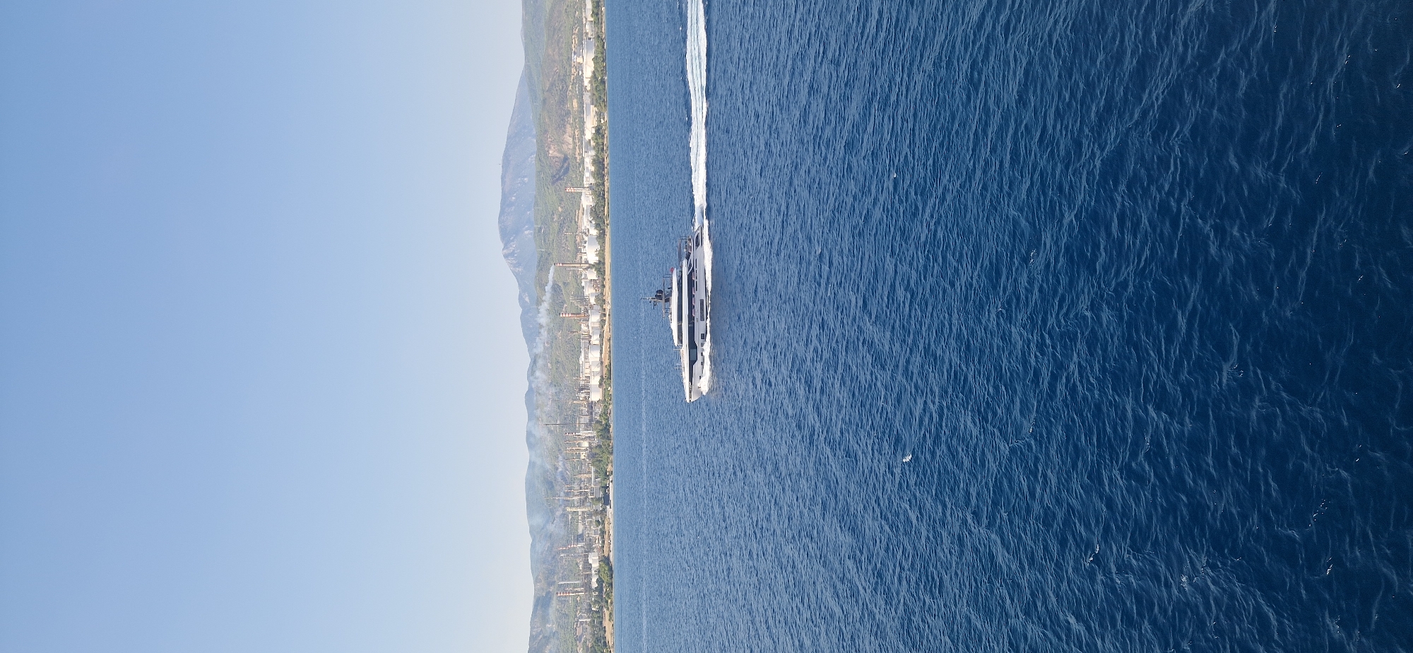 Luxury yacht passes industrial coastline near Agioi Theodoroi