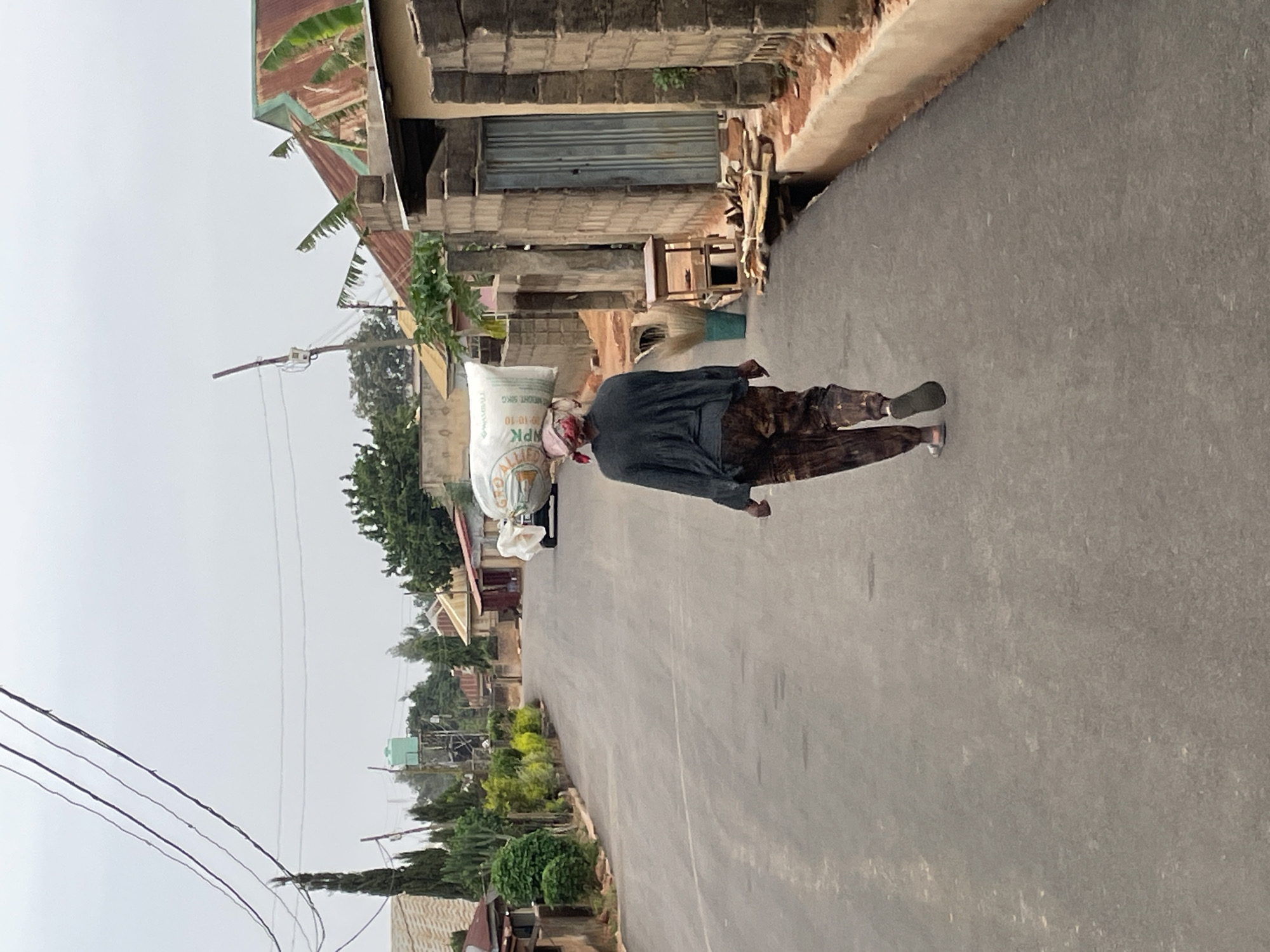 Person carries large sack while walking road in Jos