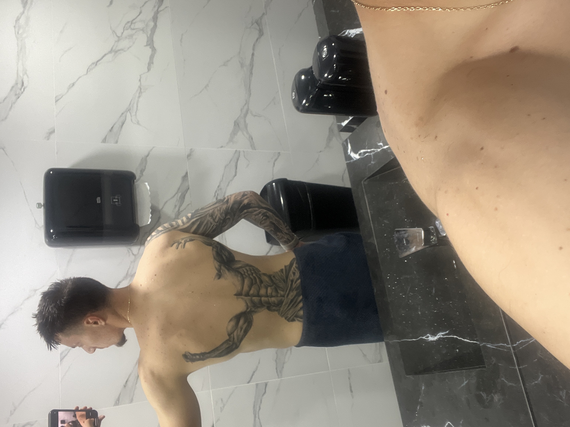 Man with back tattoo photographed in marble bathroom, Petrich