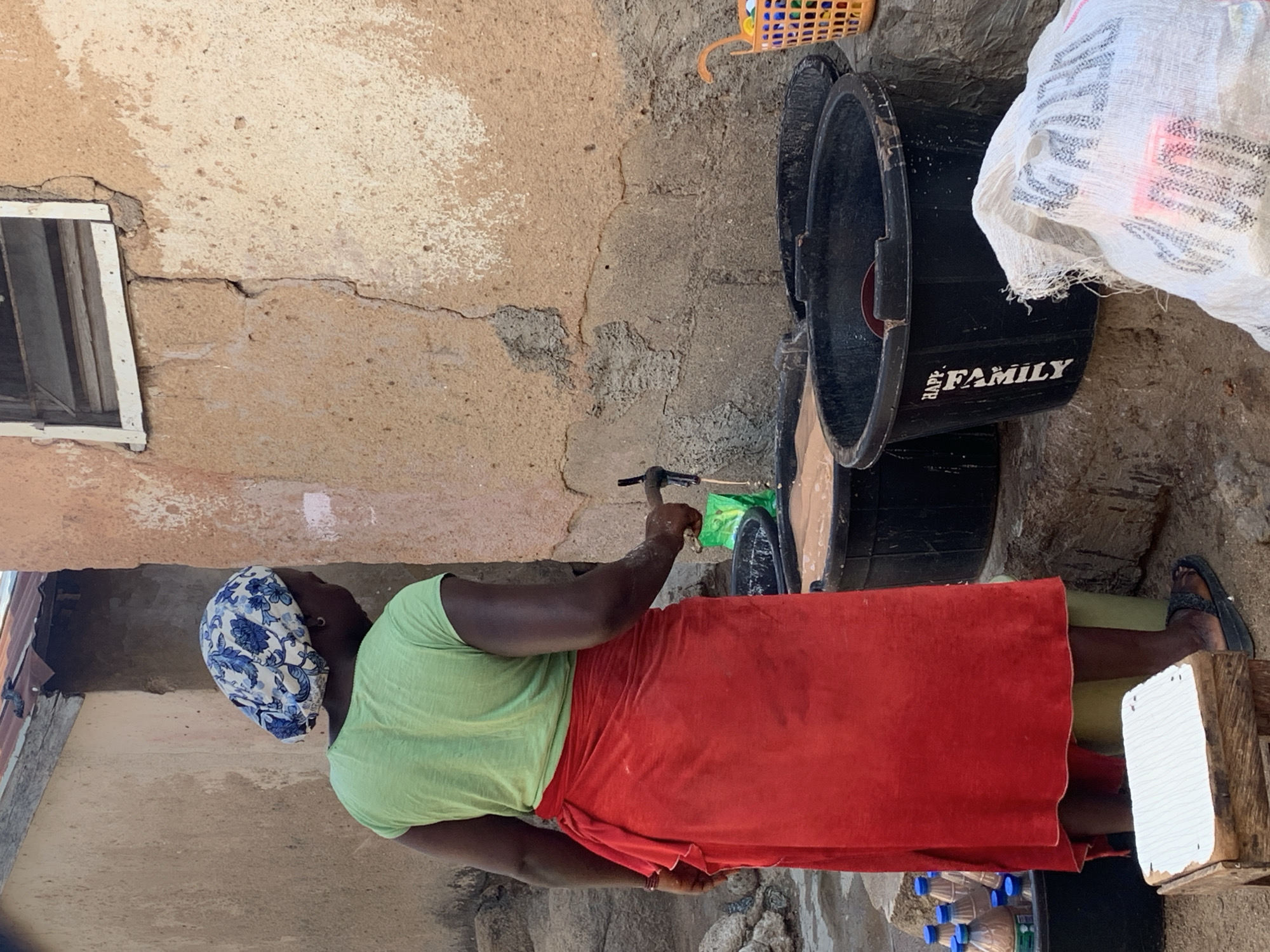 Woman transfers water using scoop near plastic tubs