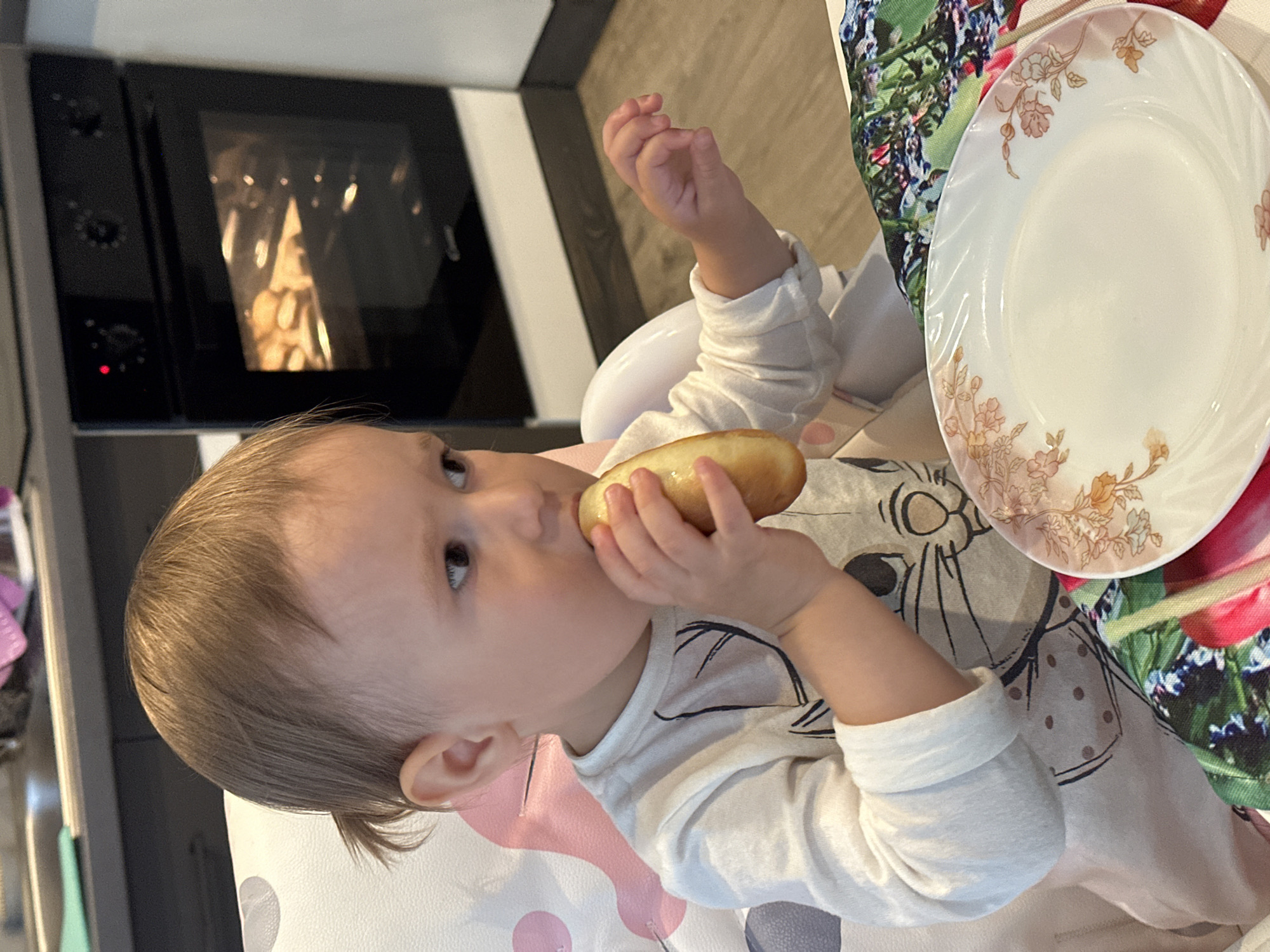 Toddler chef bakes in kitchen wearing hat, whisking batter