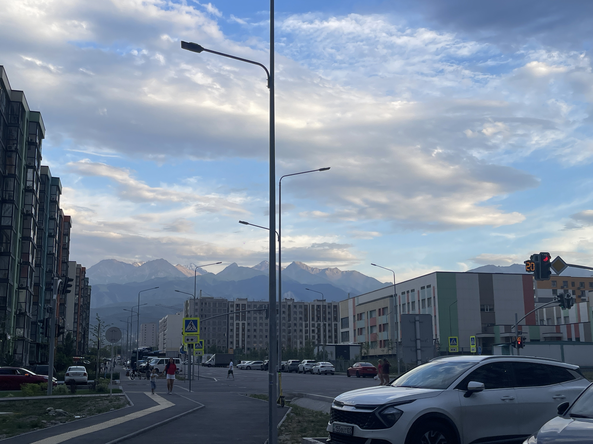 Almaty street life with mountain views on a cloudy summer afternoon