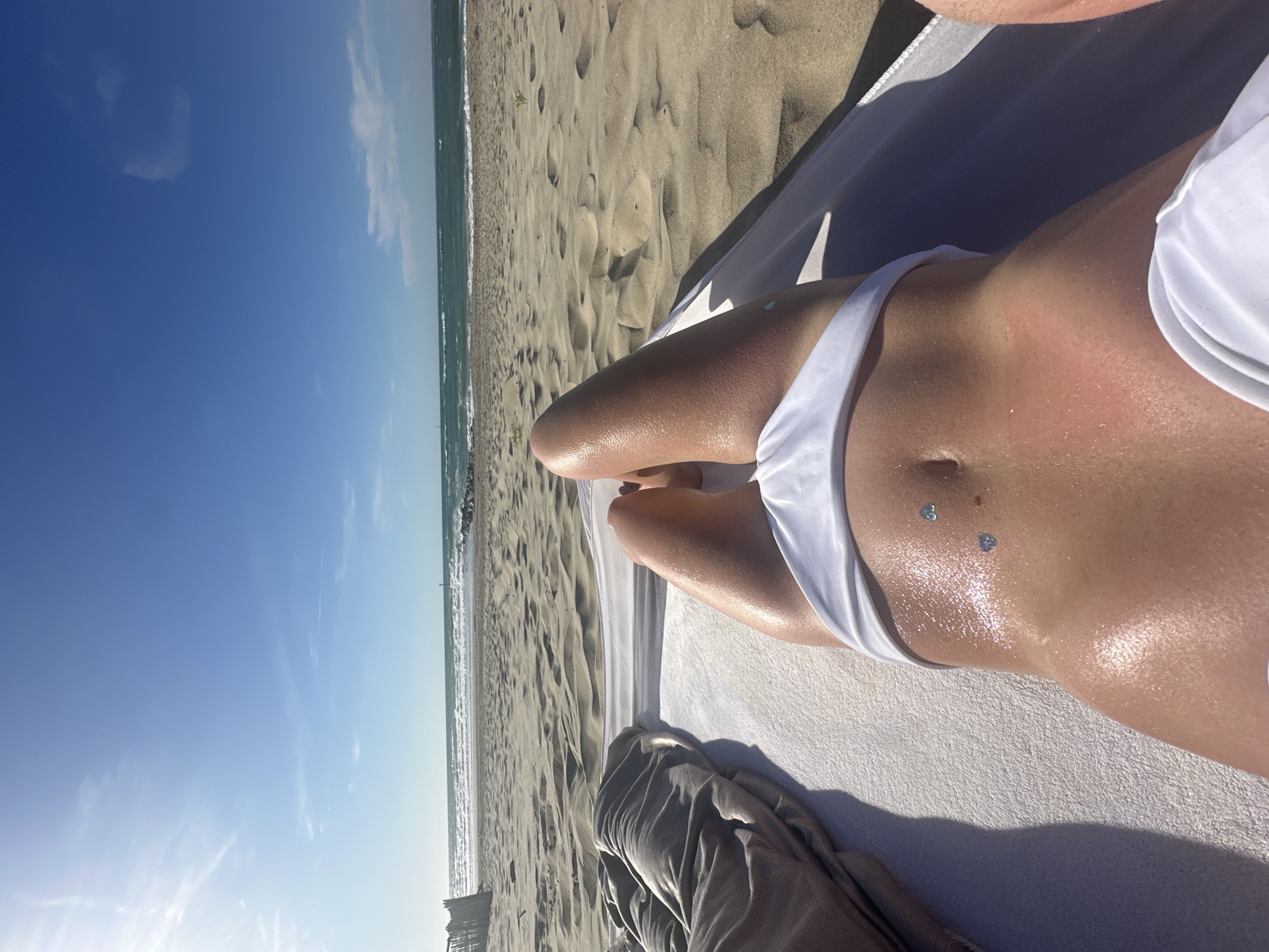 Lounging on a sandy beach, white bikini, ocean view