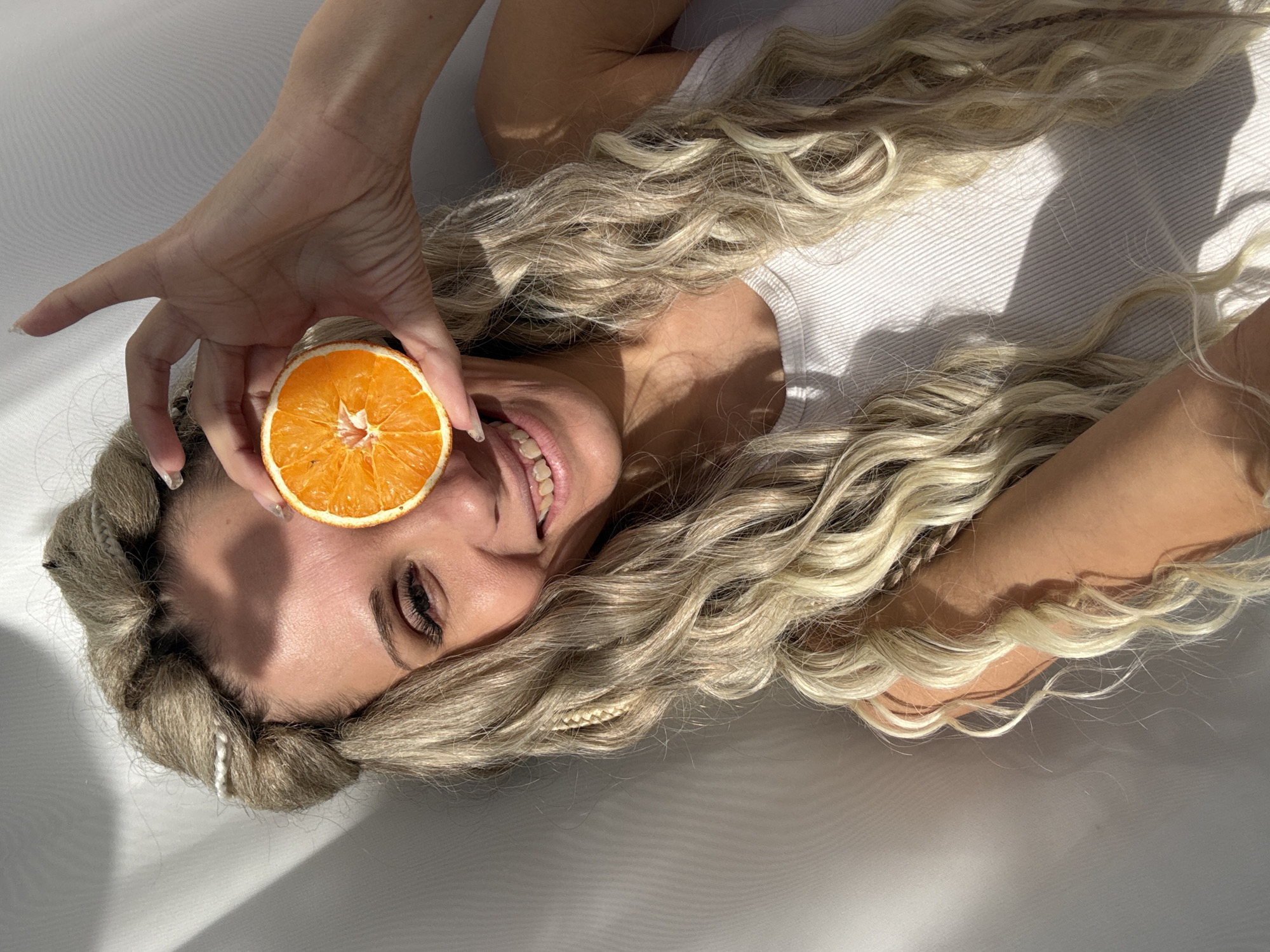 Woman photographed smiling while lying on white surface