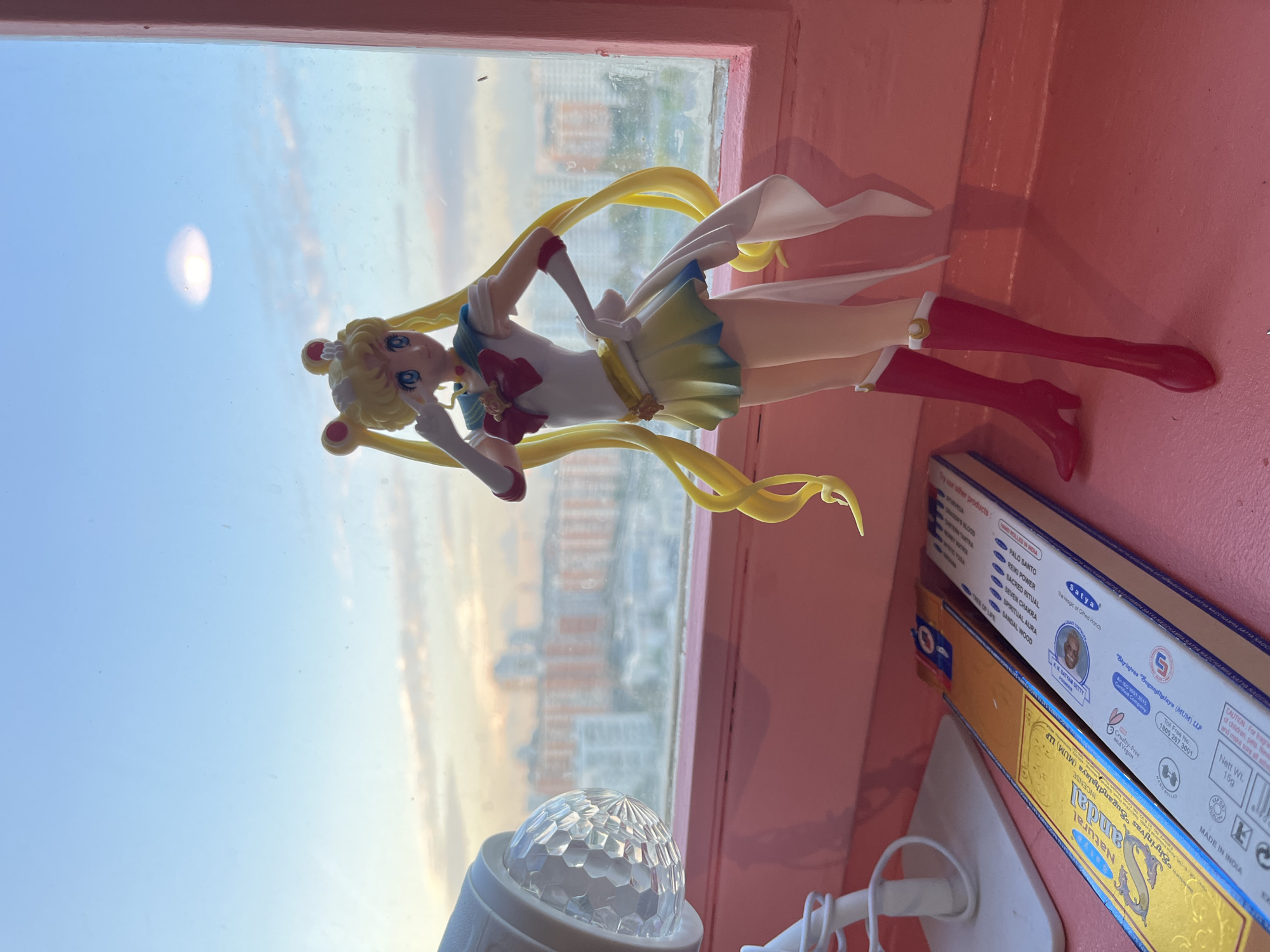 Moscow apartment windowsill with anime figures and city views at dusk