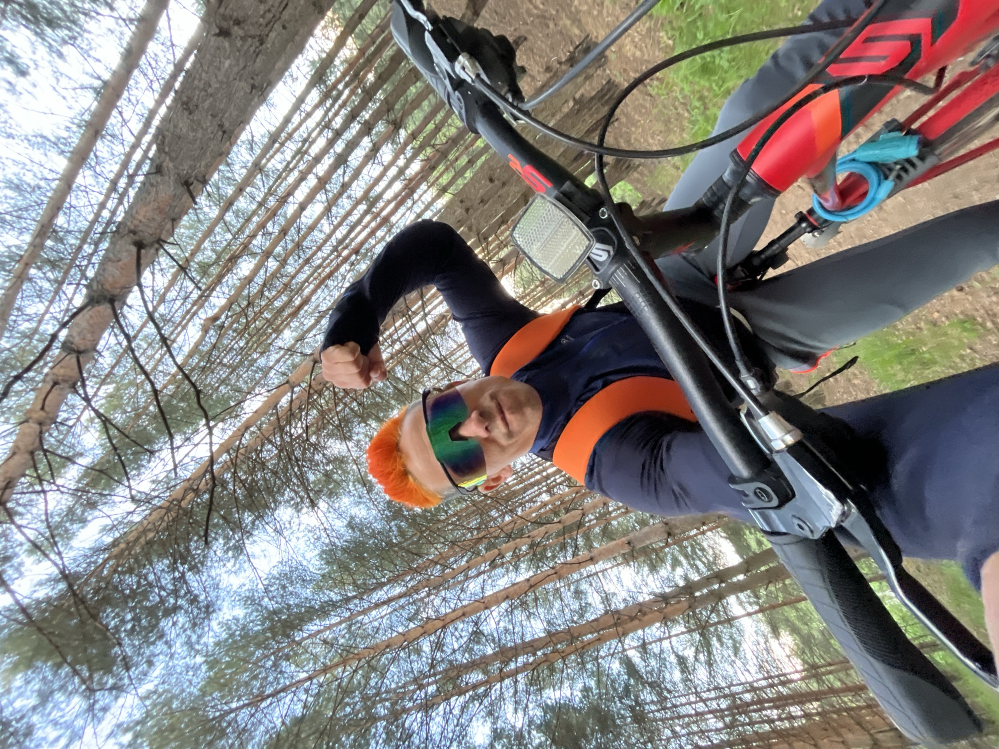 Orange-haired cyclist mountain bikes, poses for selfies near Kama River
