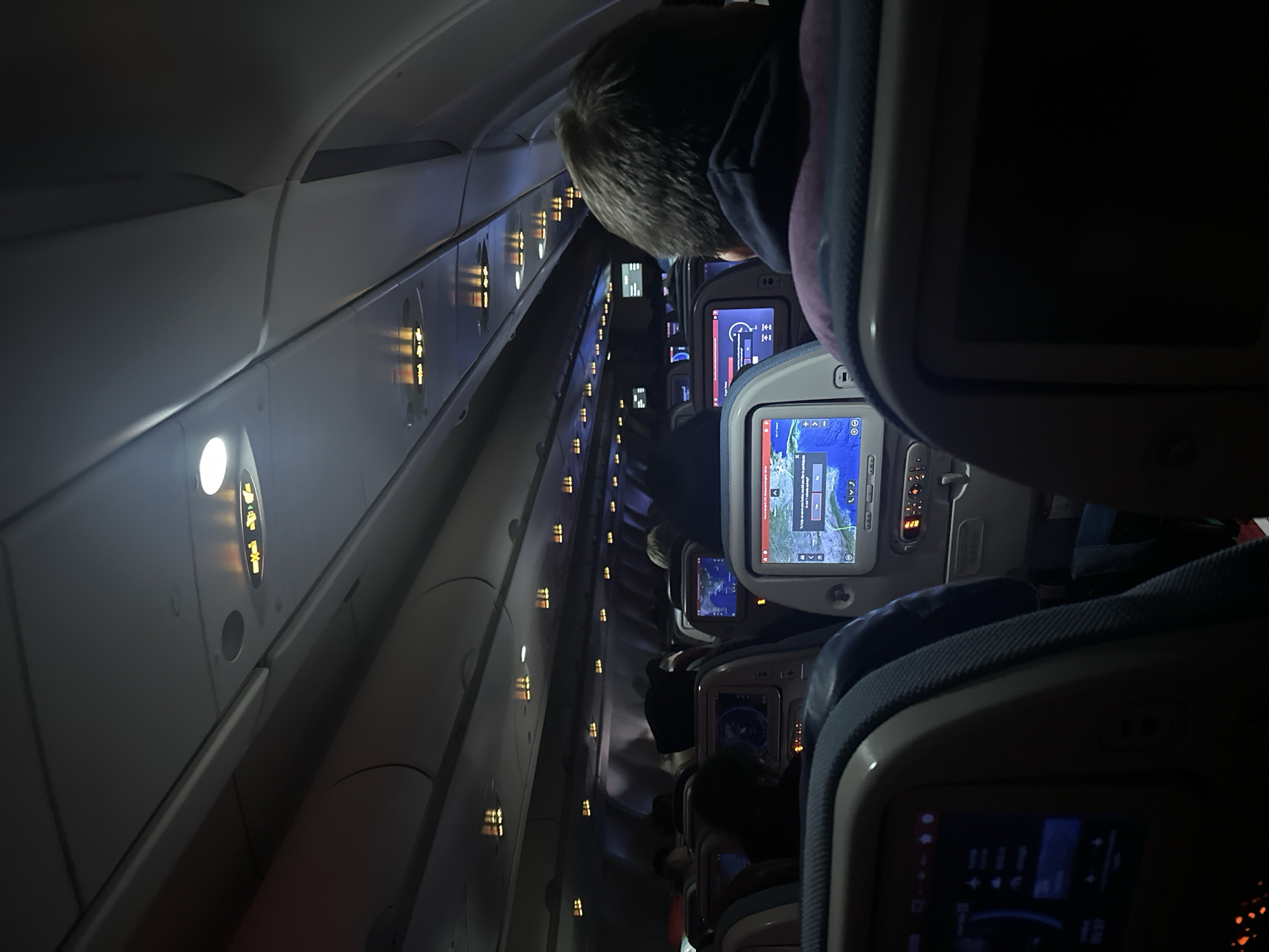 Nighttime flight cabin with seatbelt signs illuminated