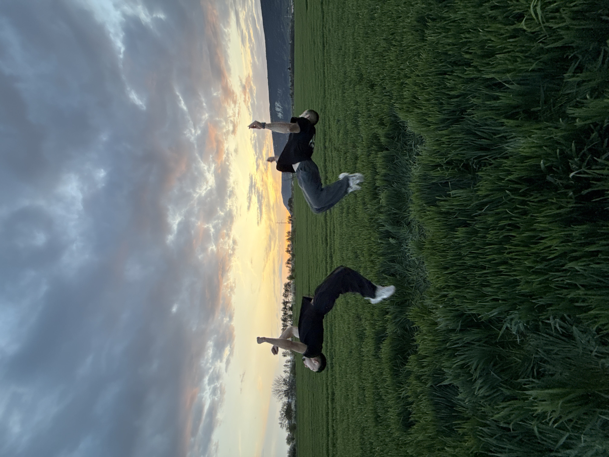 Young men perform backflips in Bulgarian field at dusk