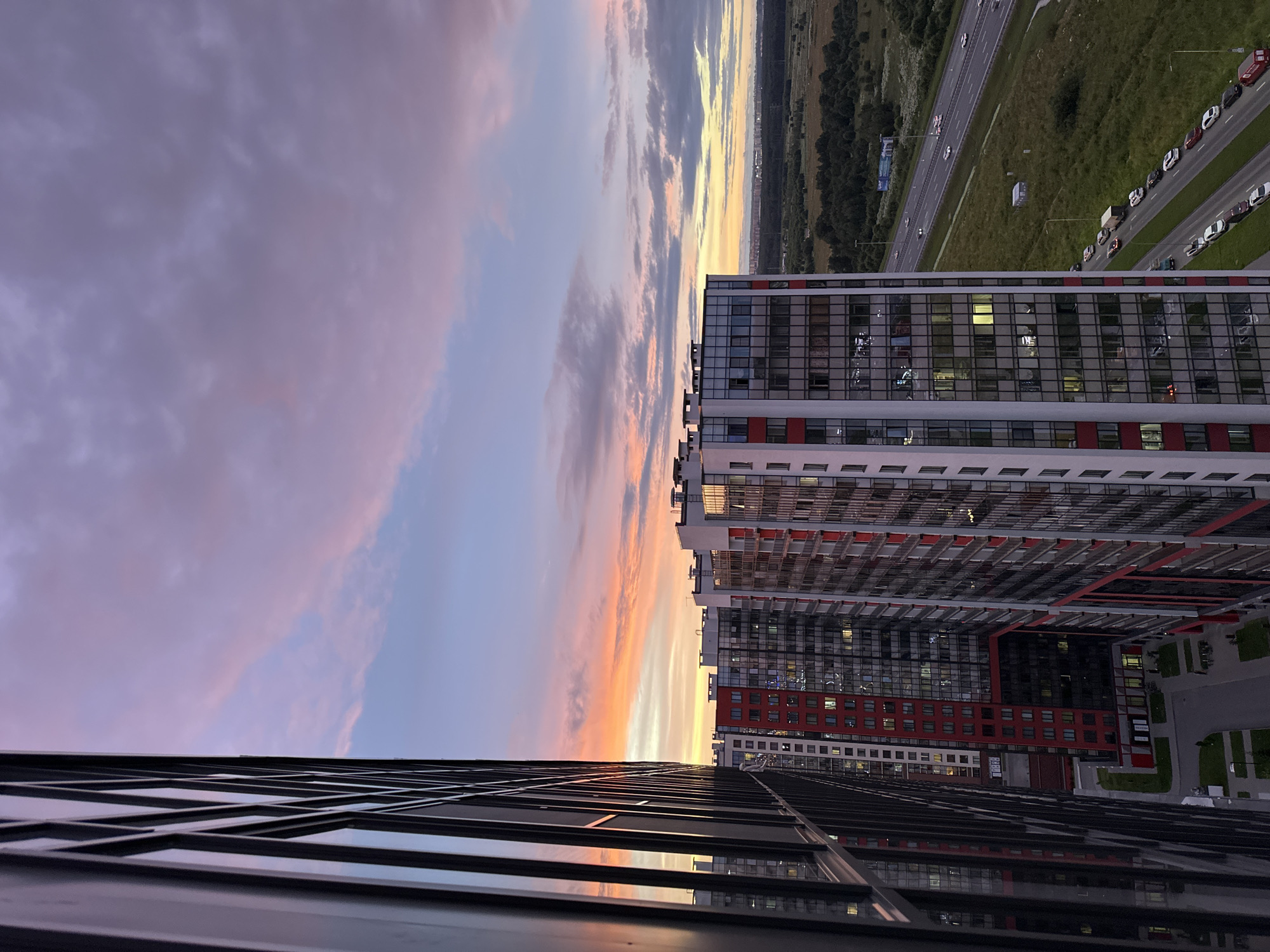 Sunset over St. Petersburg's outskirts — towers, forest, and highway
