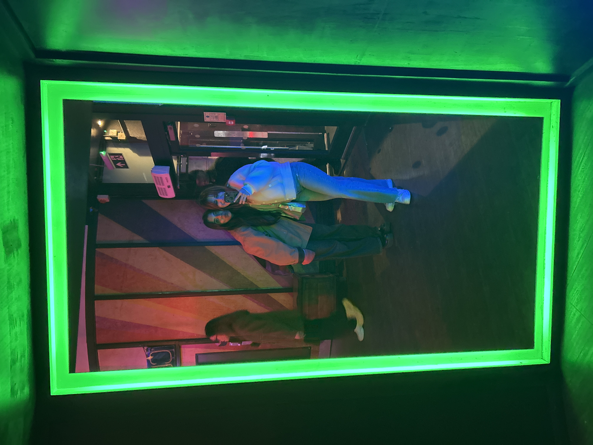 Green illuminated frame displays distorted building interior reflection in London