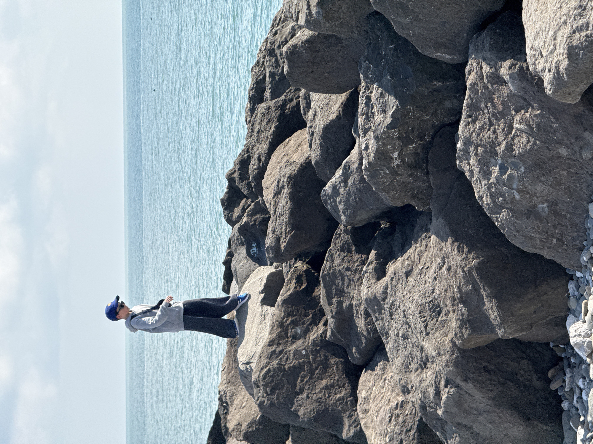 Person stands on rocks by tranquil waters in Sirius