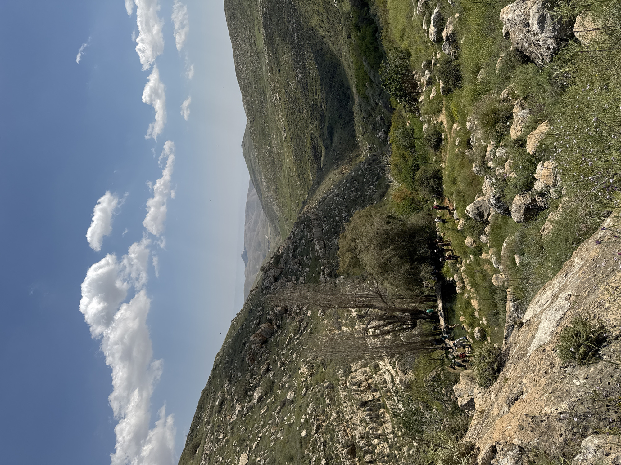 Groups gather on mountainside near Aqraba under spring skies