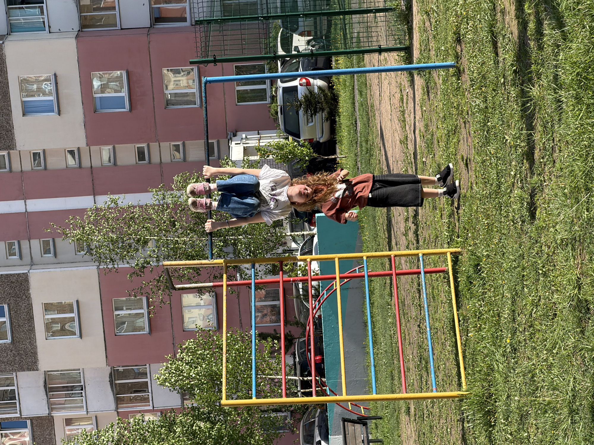 Two people hang upside down from urban monkey bars
