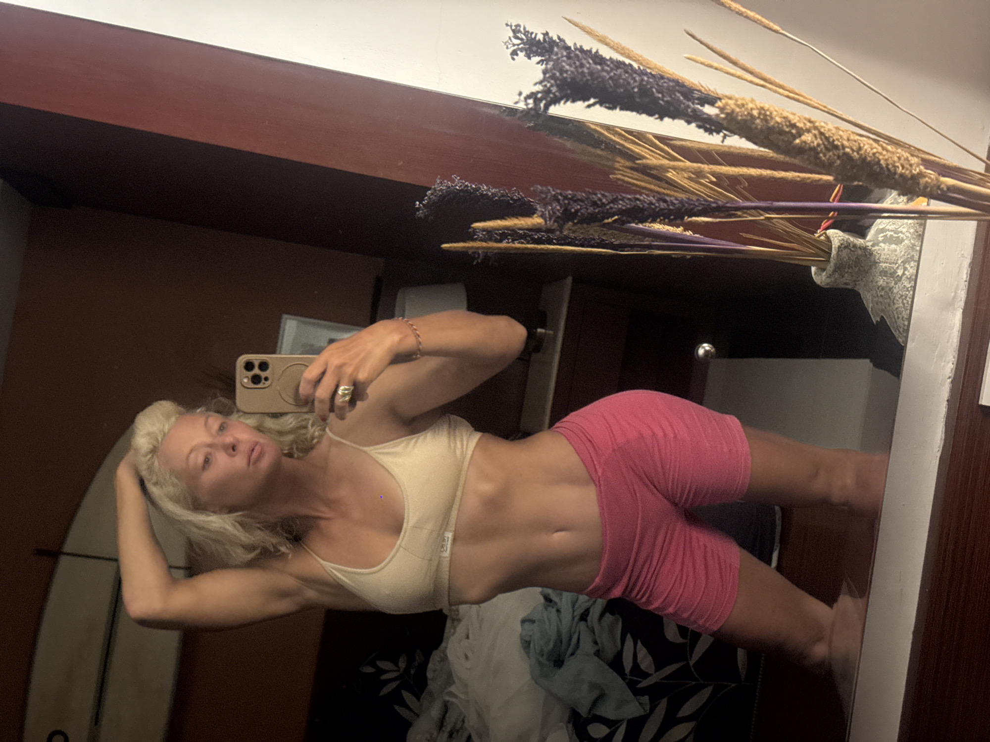 Woman takes mirror selfie in athletic wear near surfboard