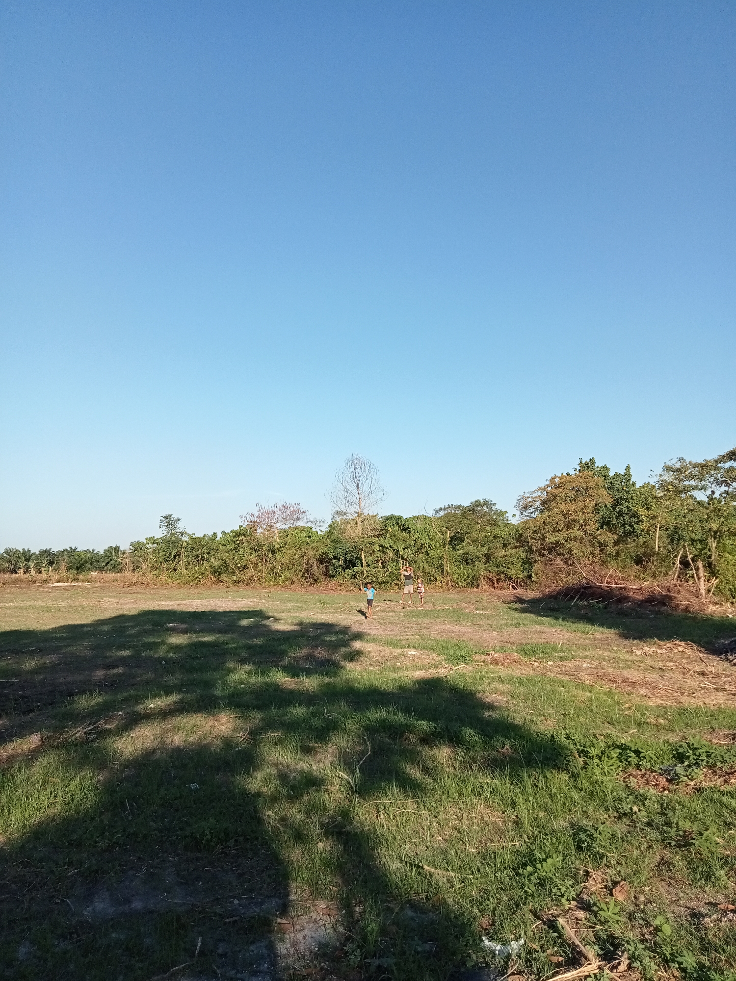 Kids exploring fields and a rusted metal structure in Kualu