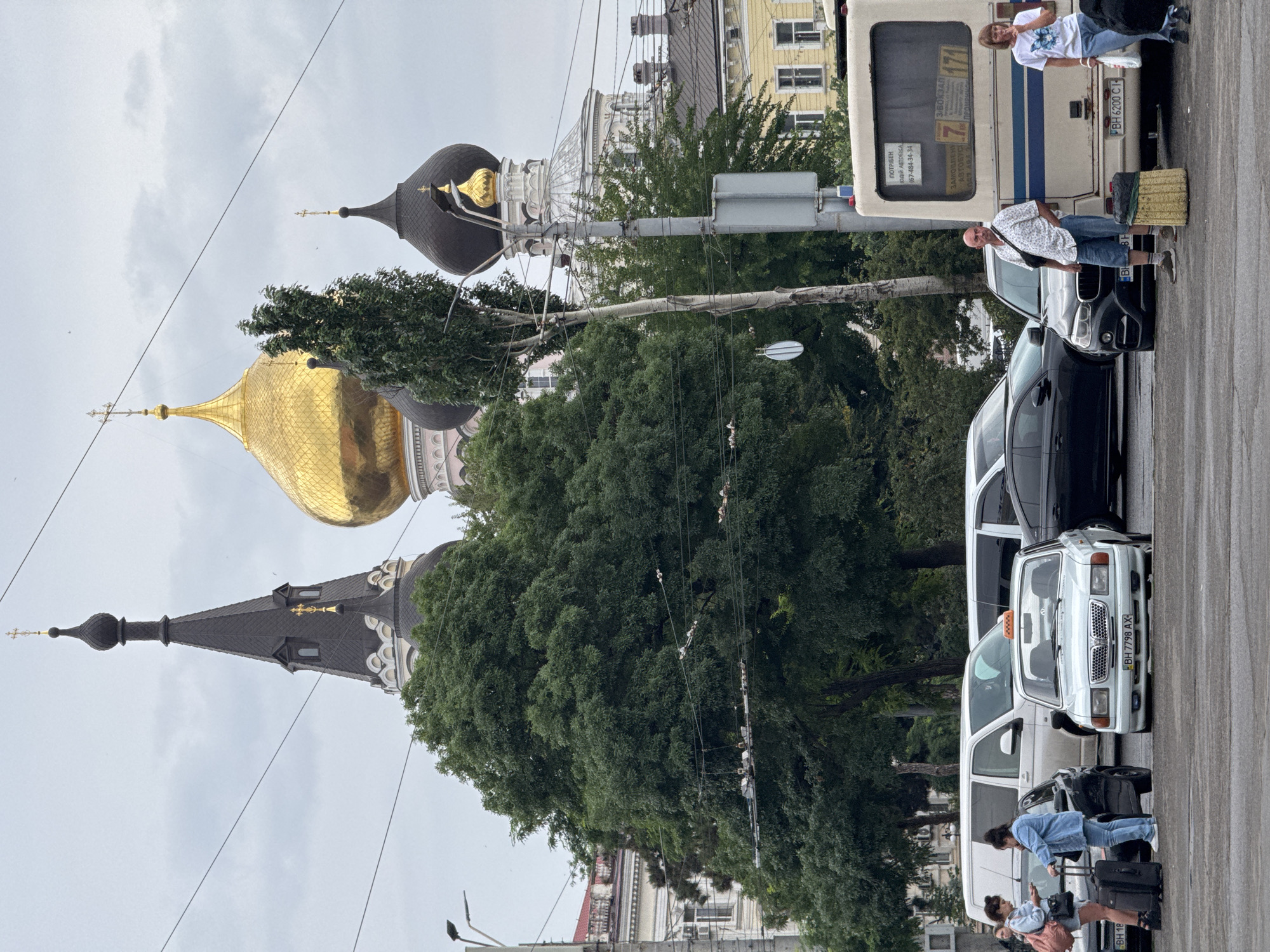 Group gathered near vehicles, church domes visible in urban background