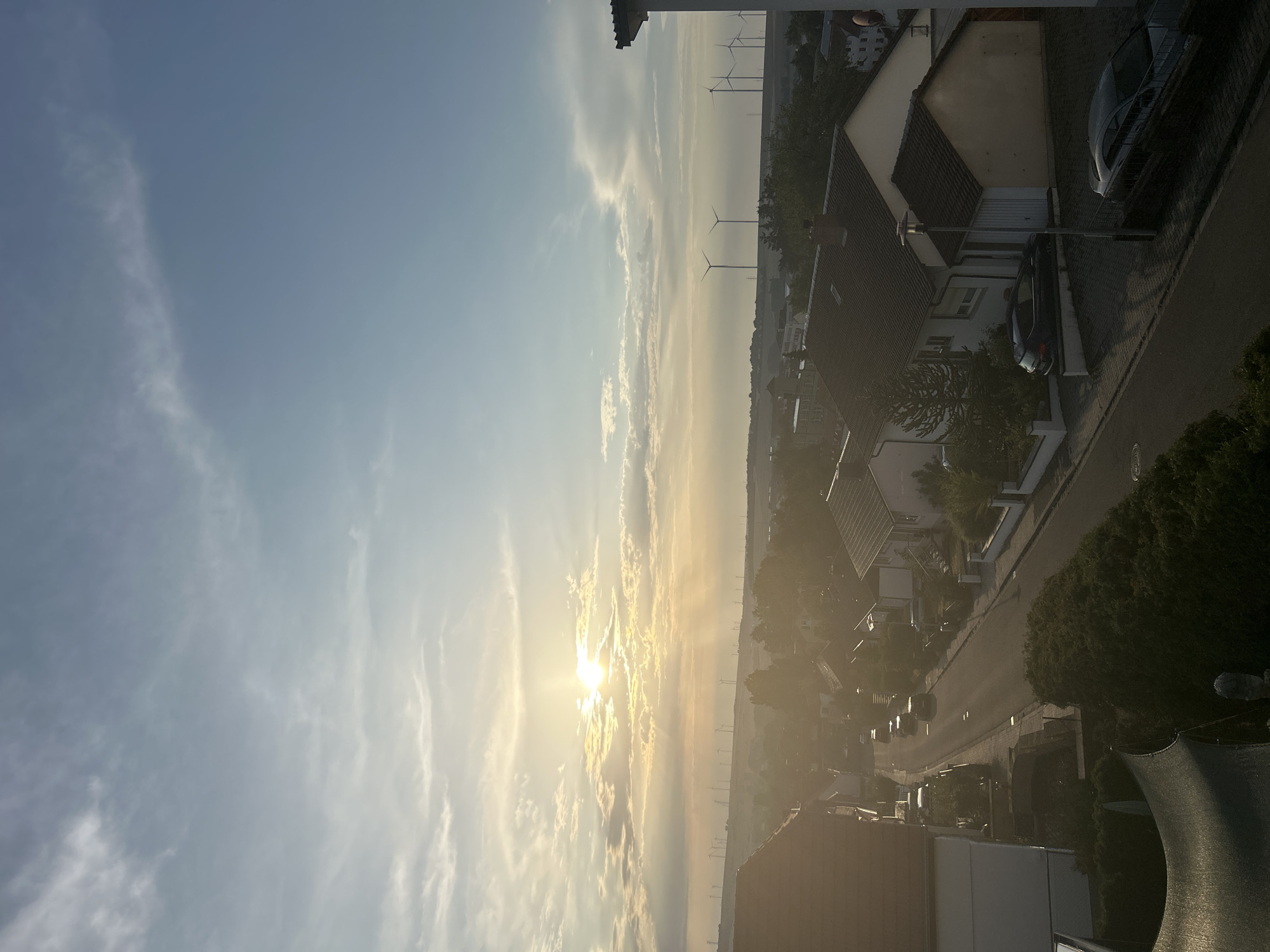Suburban evening in a European neighborhood with wind turbines and gardens