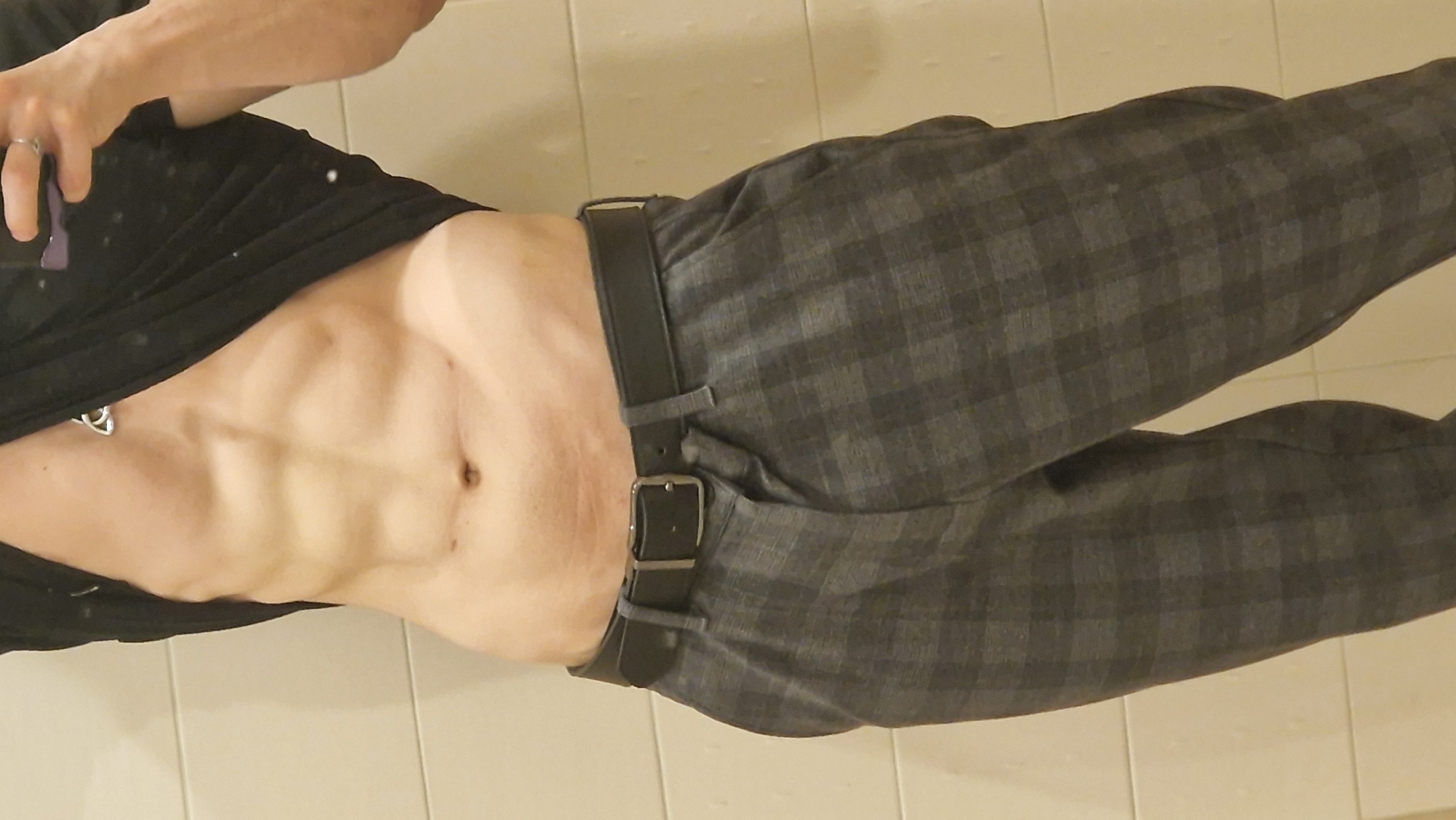 Person poses with exposed torso in tiled indoor space