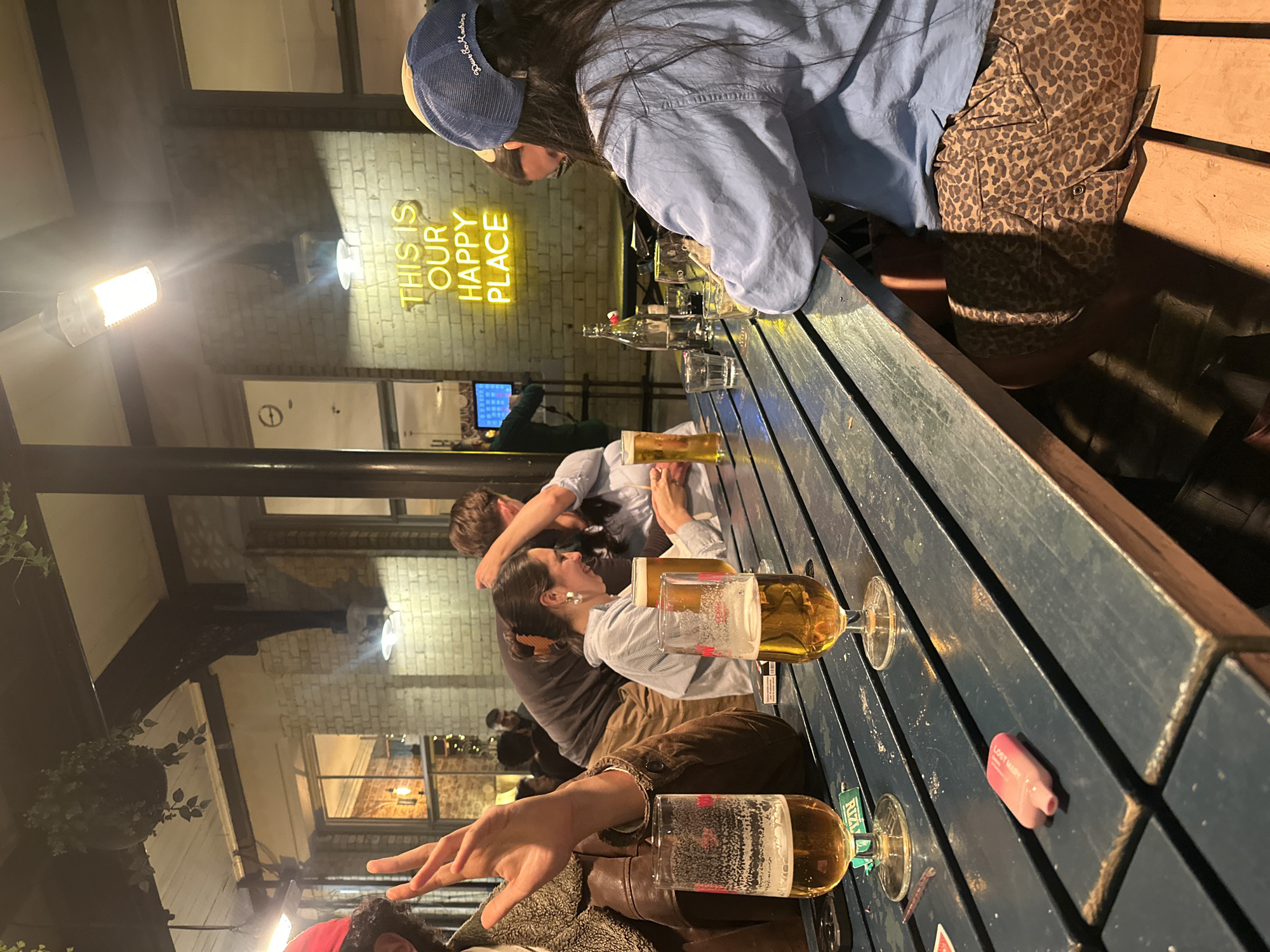 Evening gathering at London outdoor bar with neon signage
