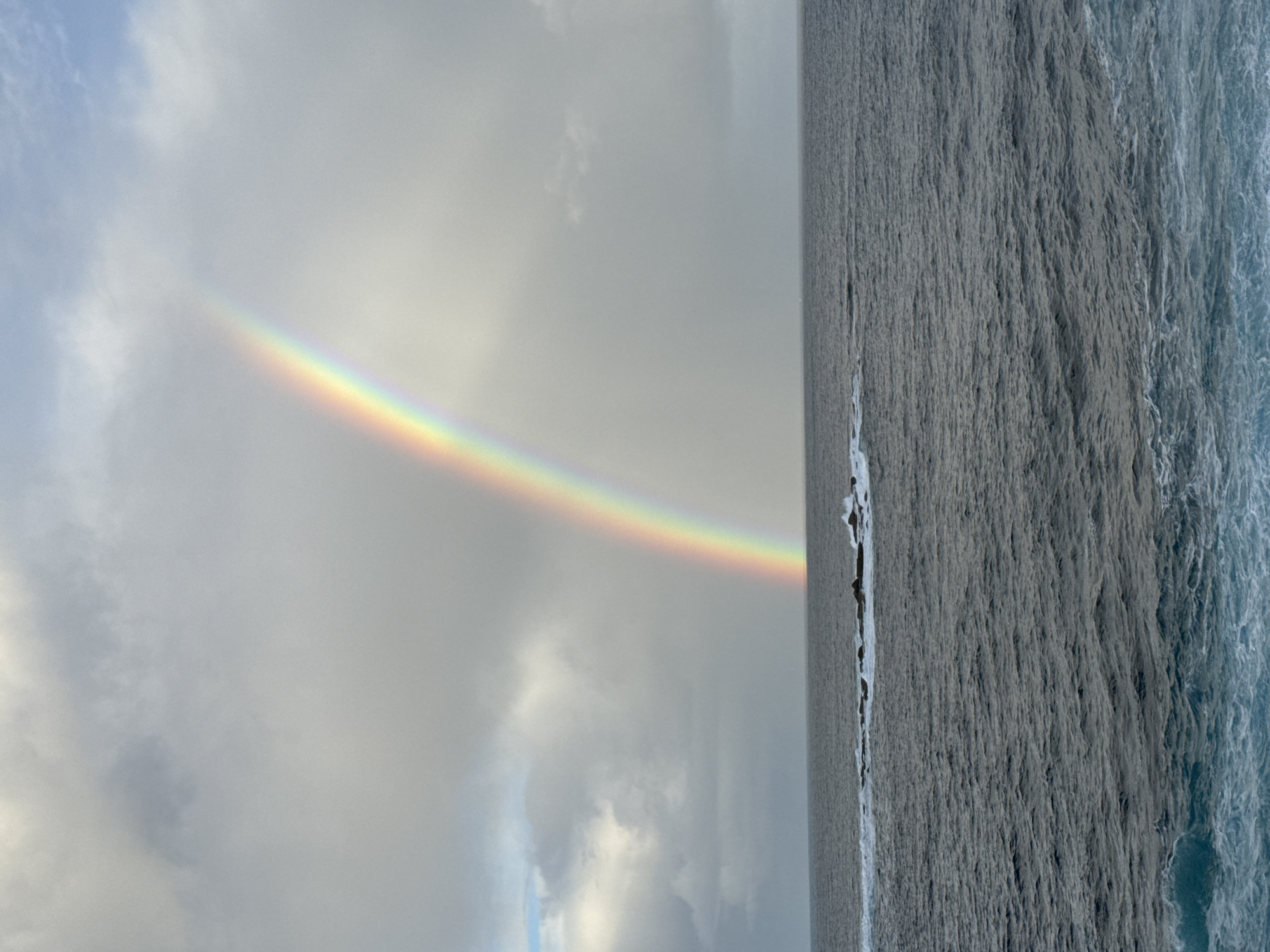 Rainbow over turbulent seas at Clovelly coast