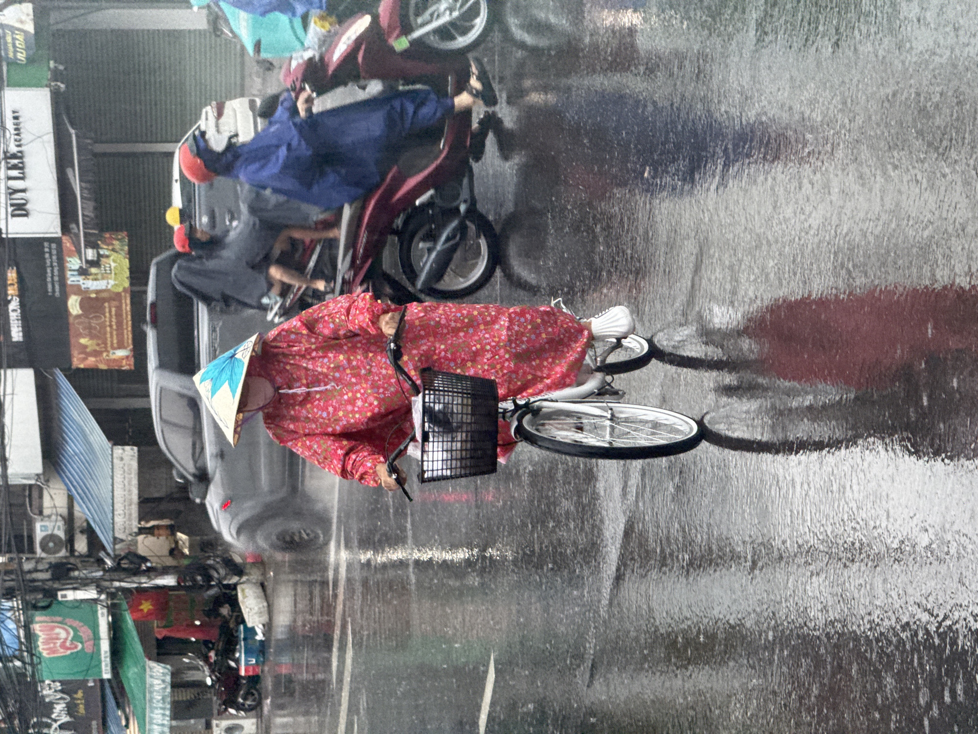 Cyclists navigate rainy streets in Bac Nha Trang Ward