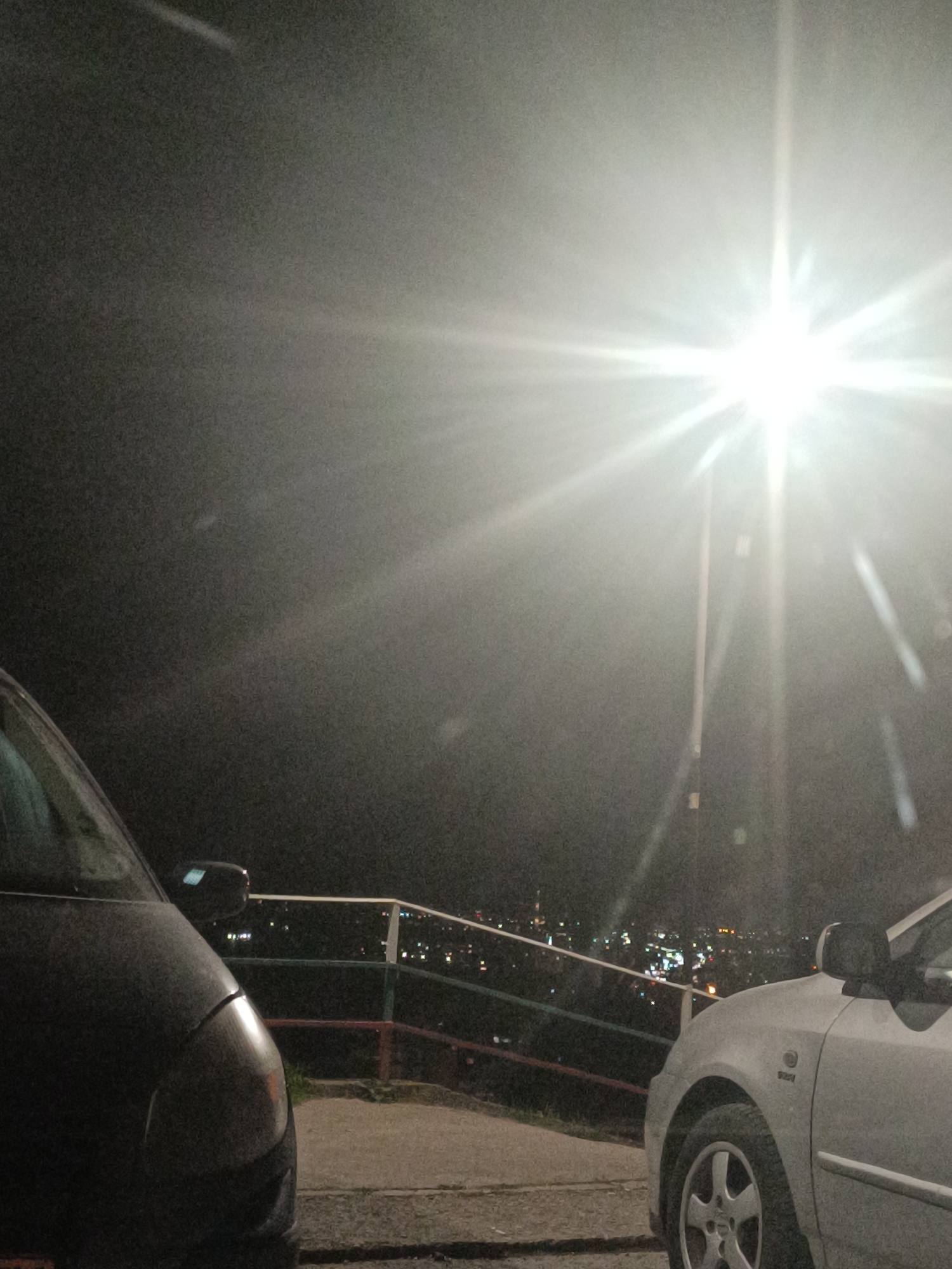 Cars parked at city viewpoint during evening hours