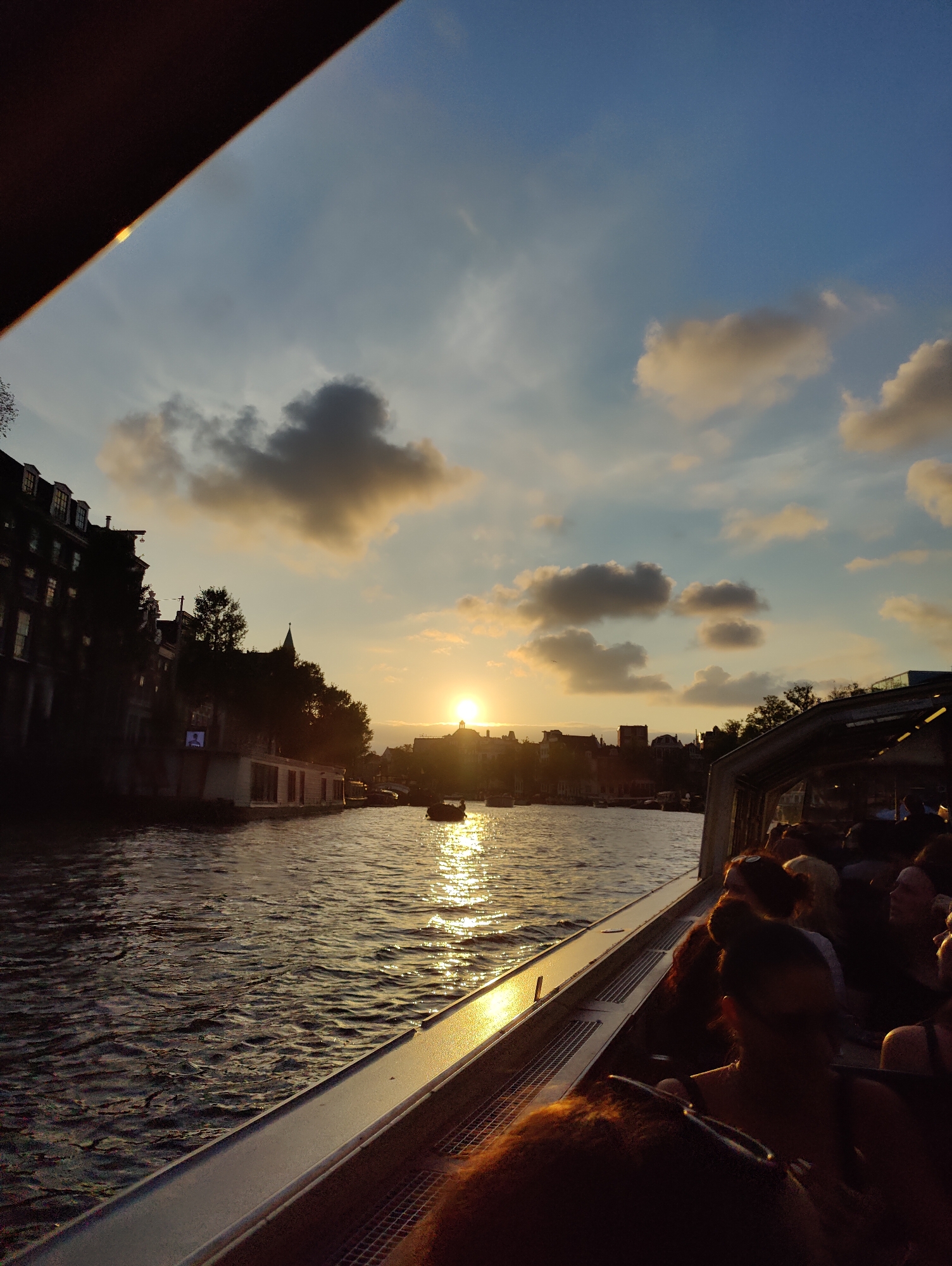 Sunset canal cruising in Amsterdam, July evening.