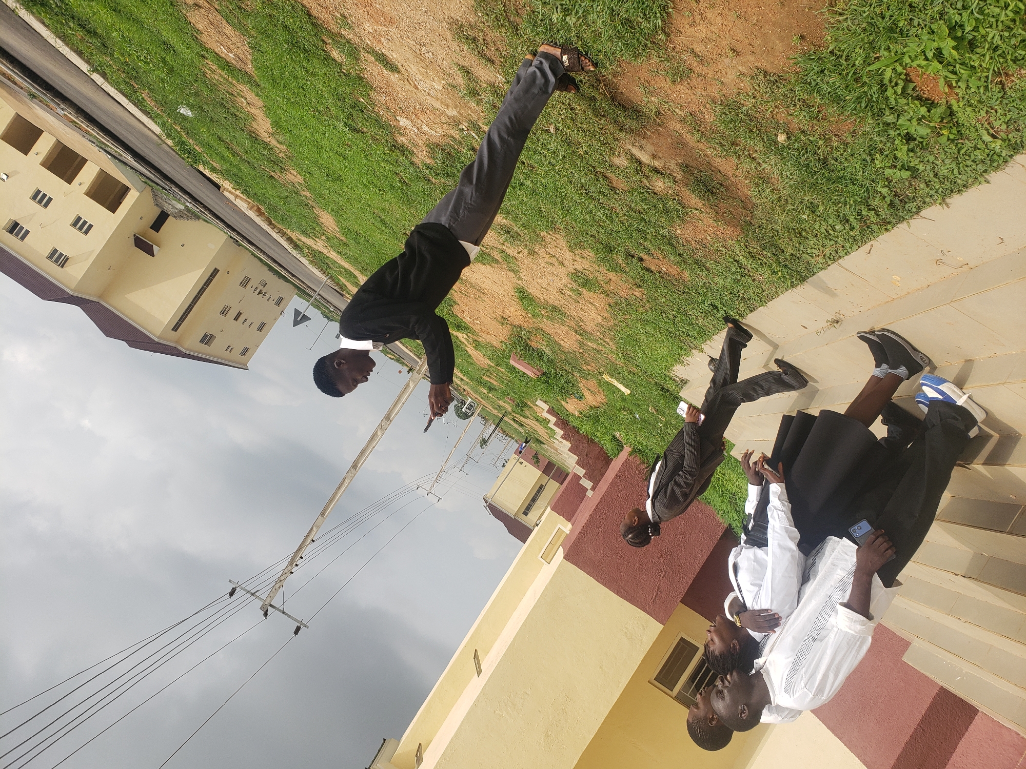 Four people gather on building stairs in Gumel, Nigeria
