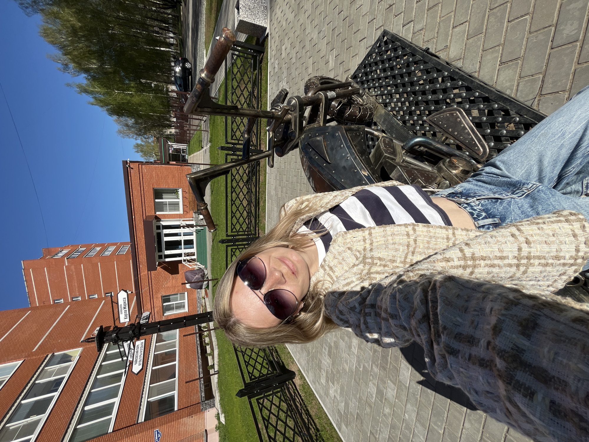 Visitors pose with metal motorcycle sculpture in Chaikovsky park