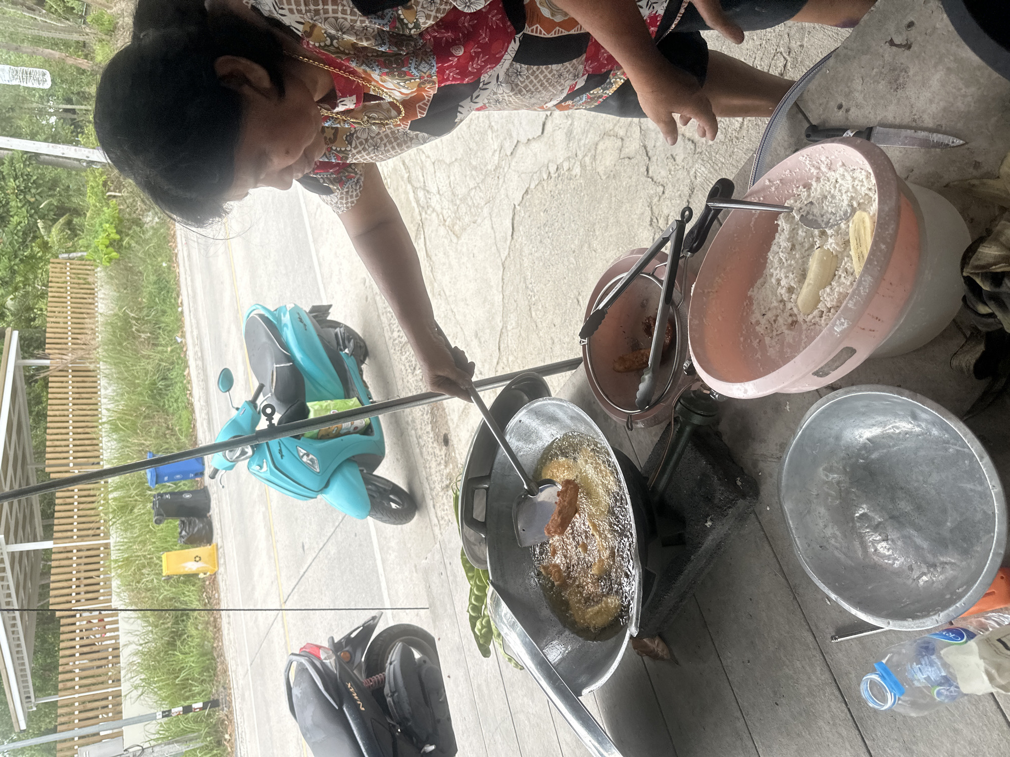 Woman fries banana fritters outdoors in Ko Phangan, Thailand