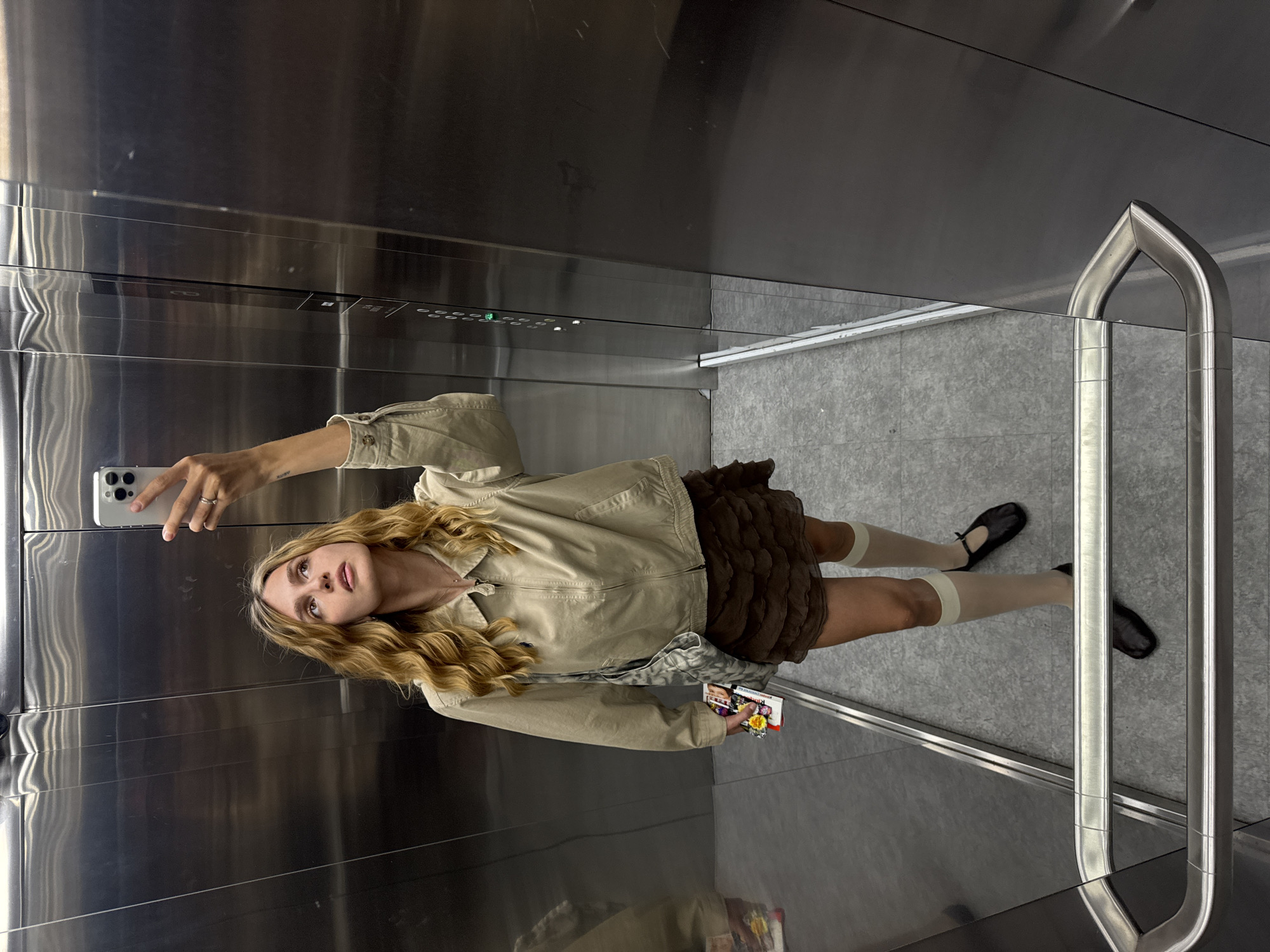 Woman takes elevator selfie in stainless steel interior