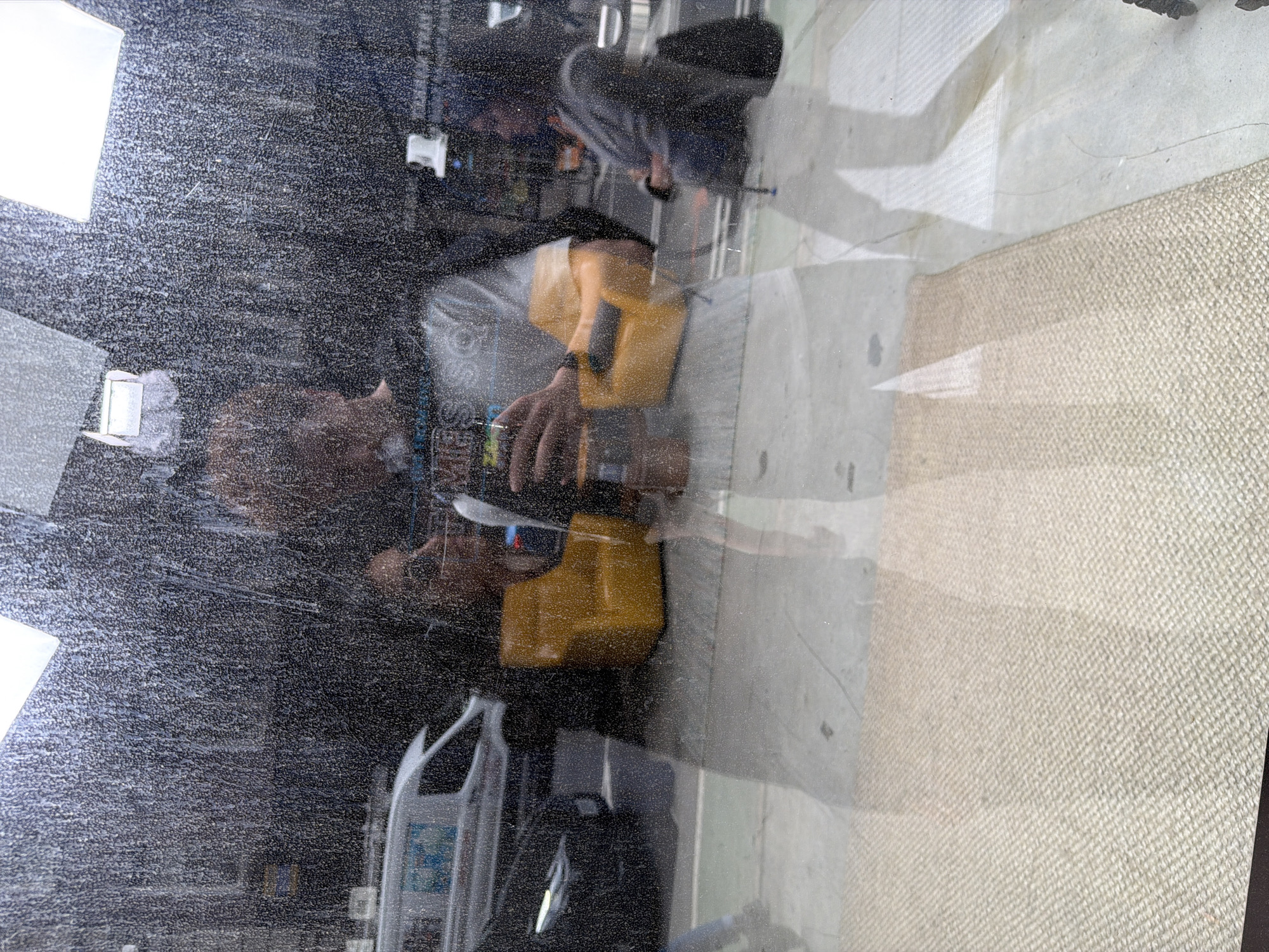 Person with yellow container photographed through dirty window in NYC