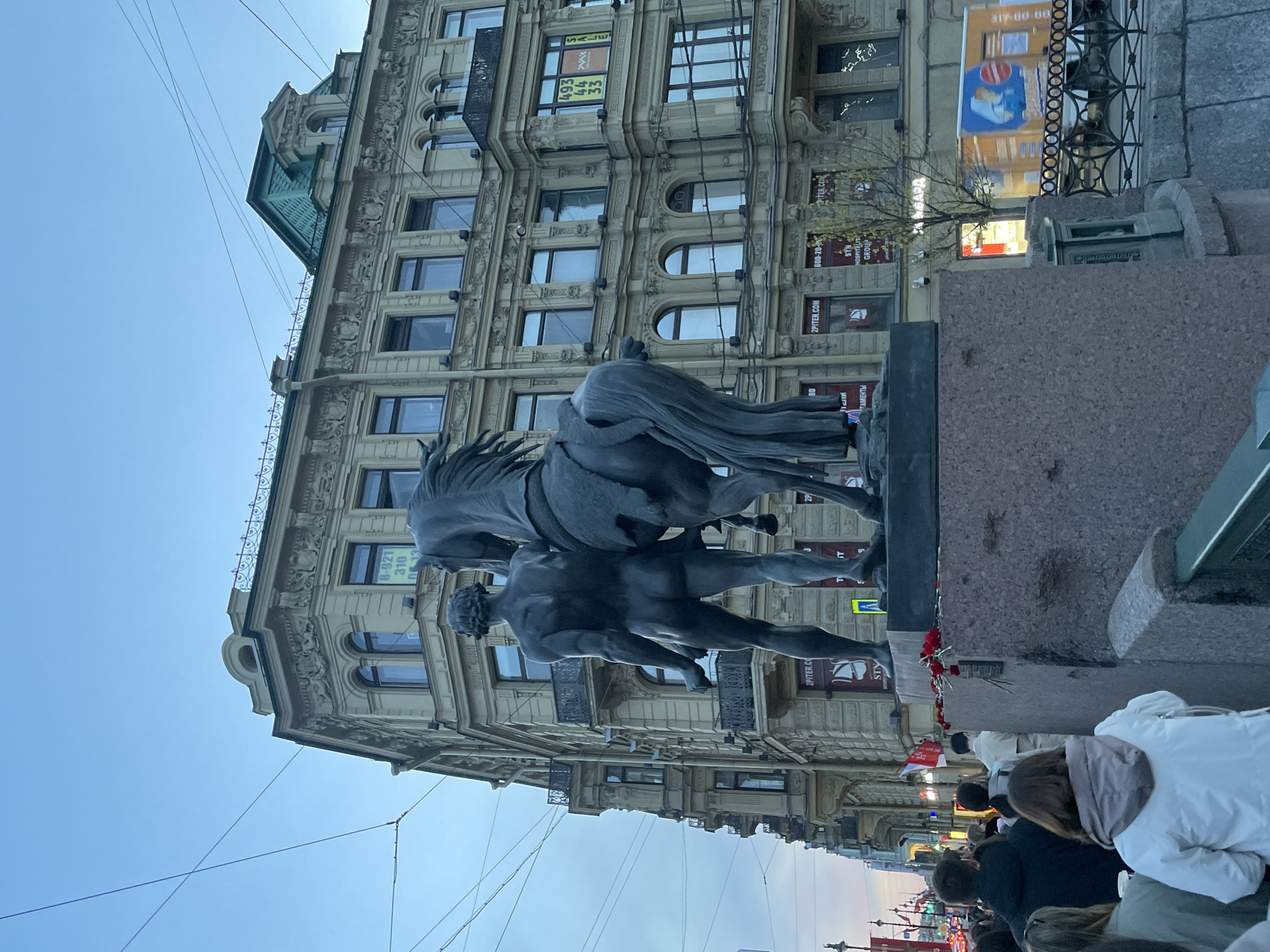 Evening pedestrian activity documented near historic statues in Saint Petersburg