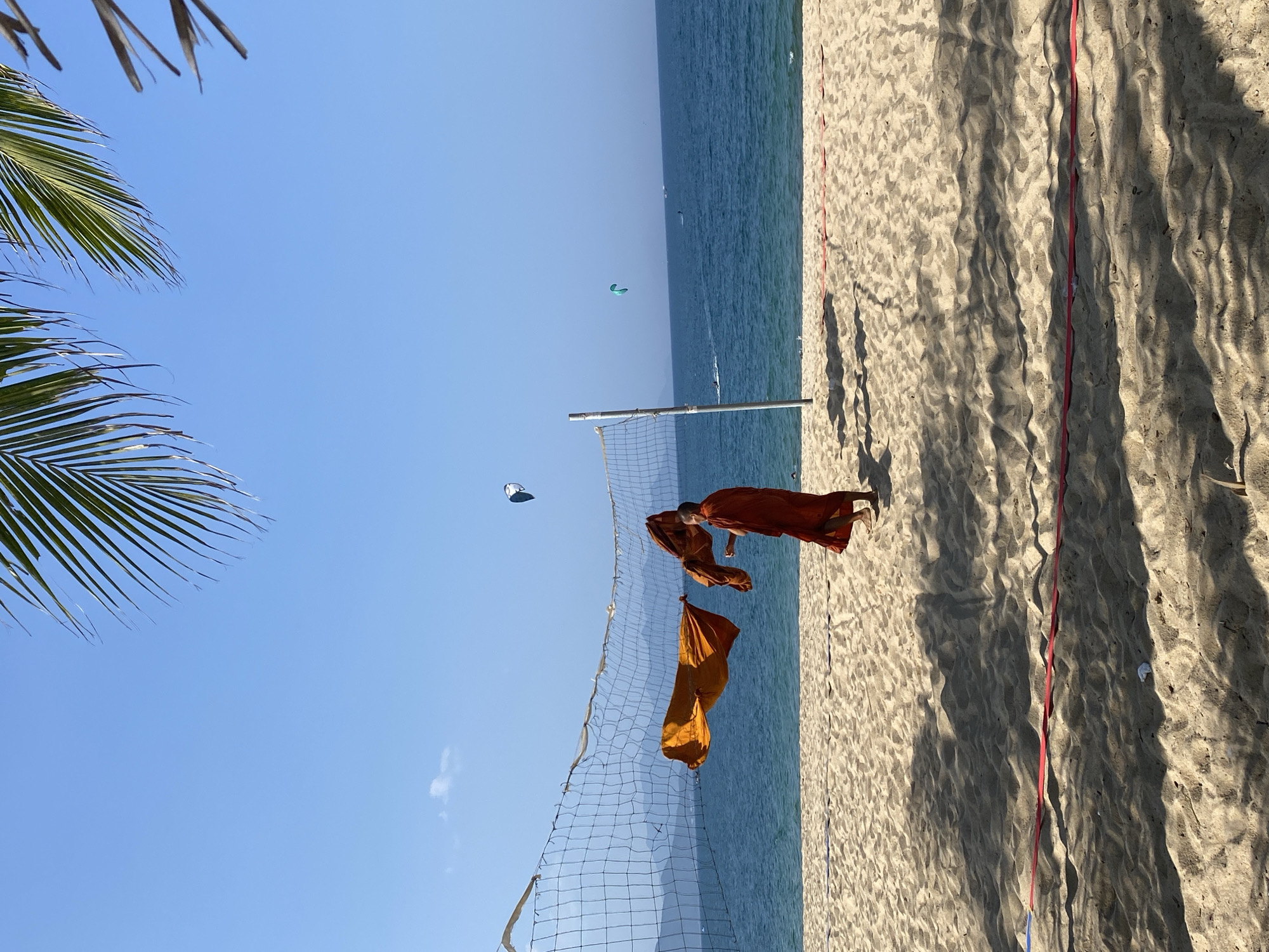 Nha Trang beach morning: kitesurfers, palm shadows, and a monk on the sand
