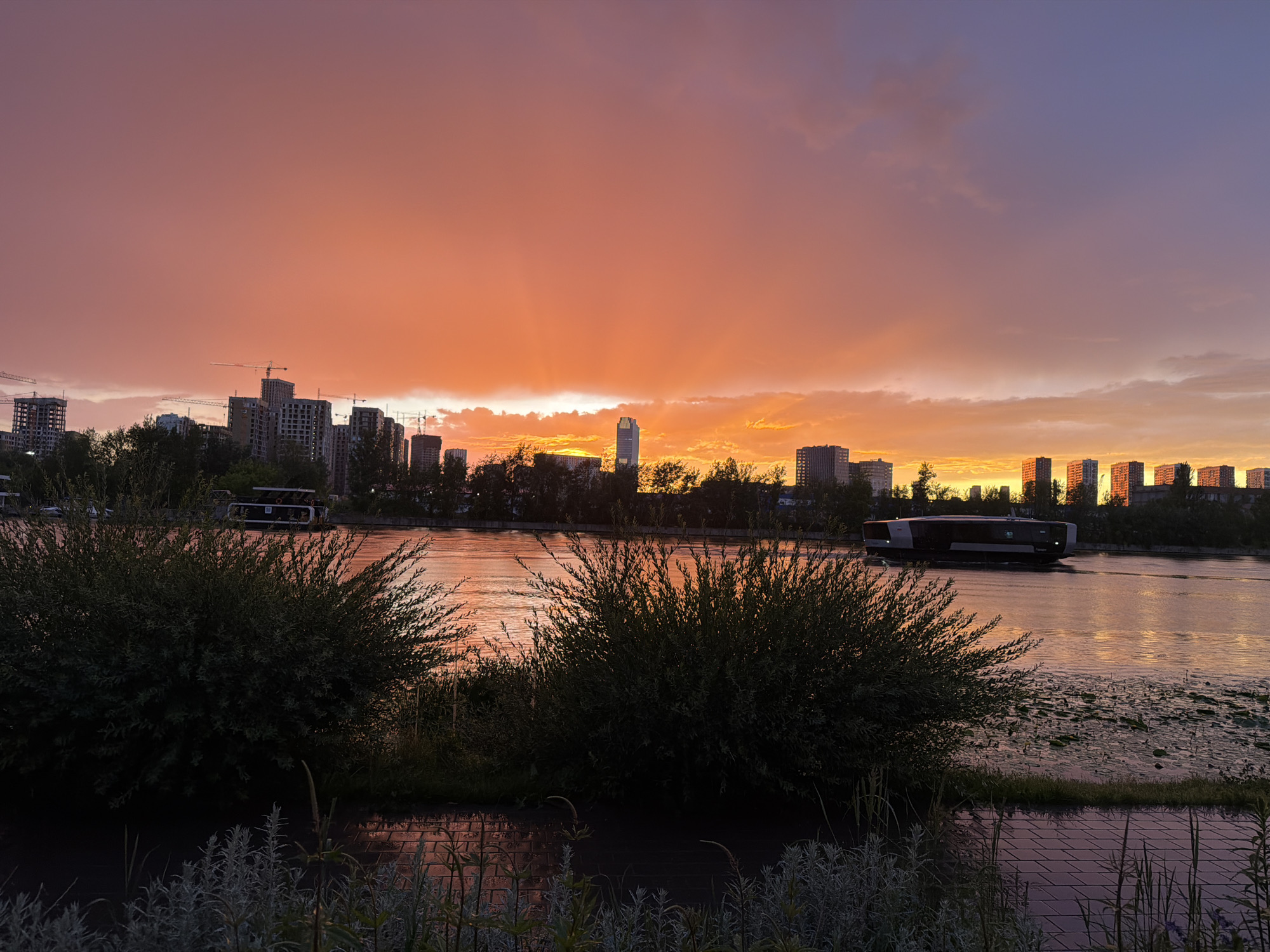 Moscow riverfront at golden hour, cranes and a rainbow