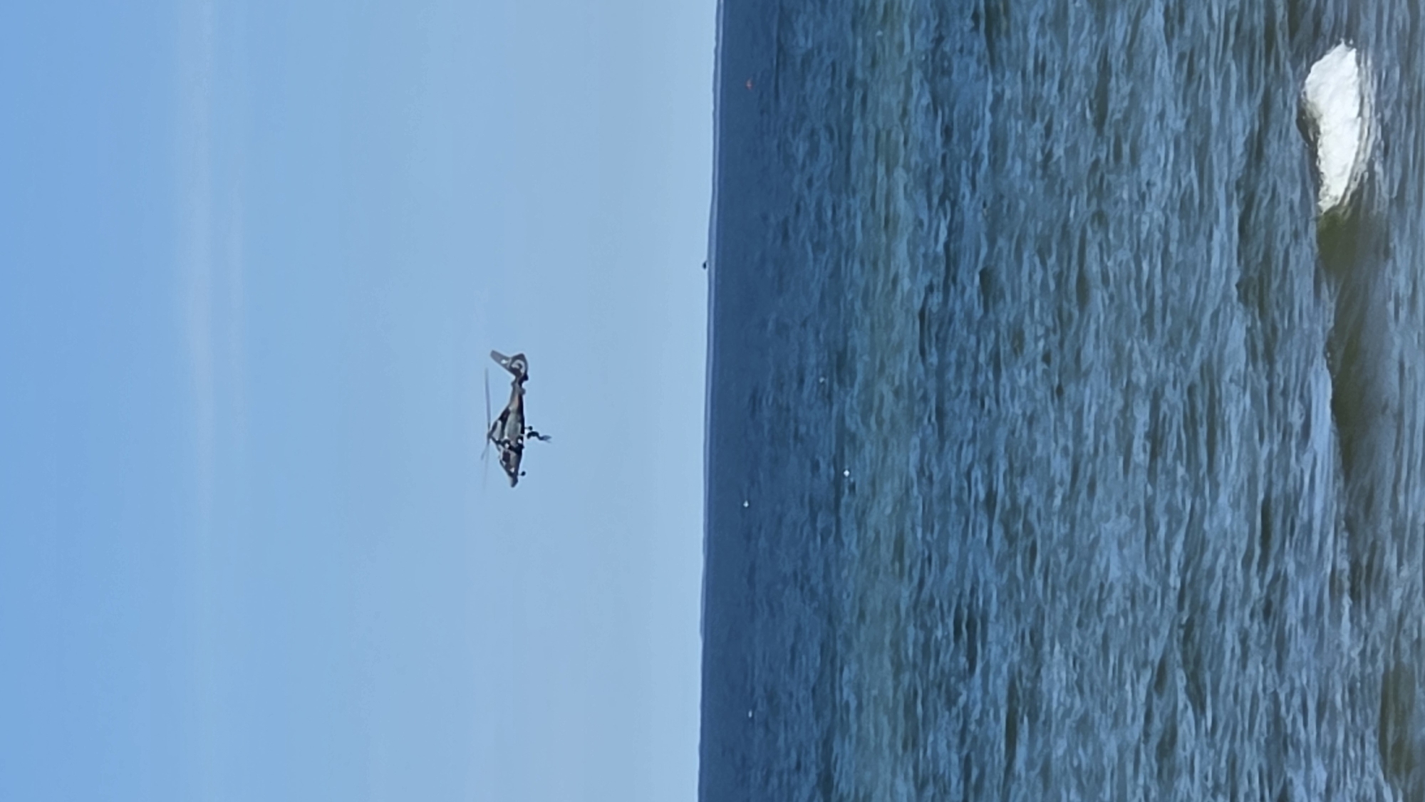 Helicopter rescue operation plays out over the ocean near a beach