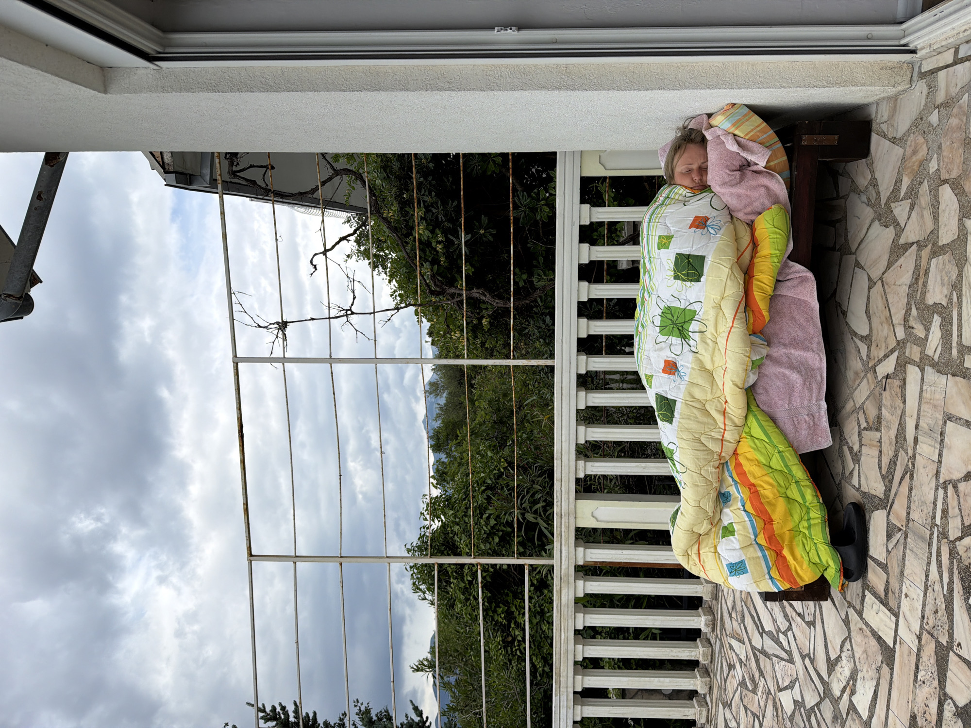 Woman naps on balcony bench in Montenegro village