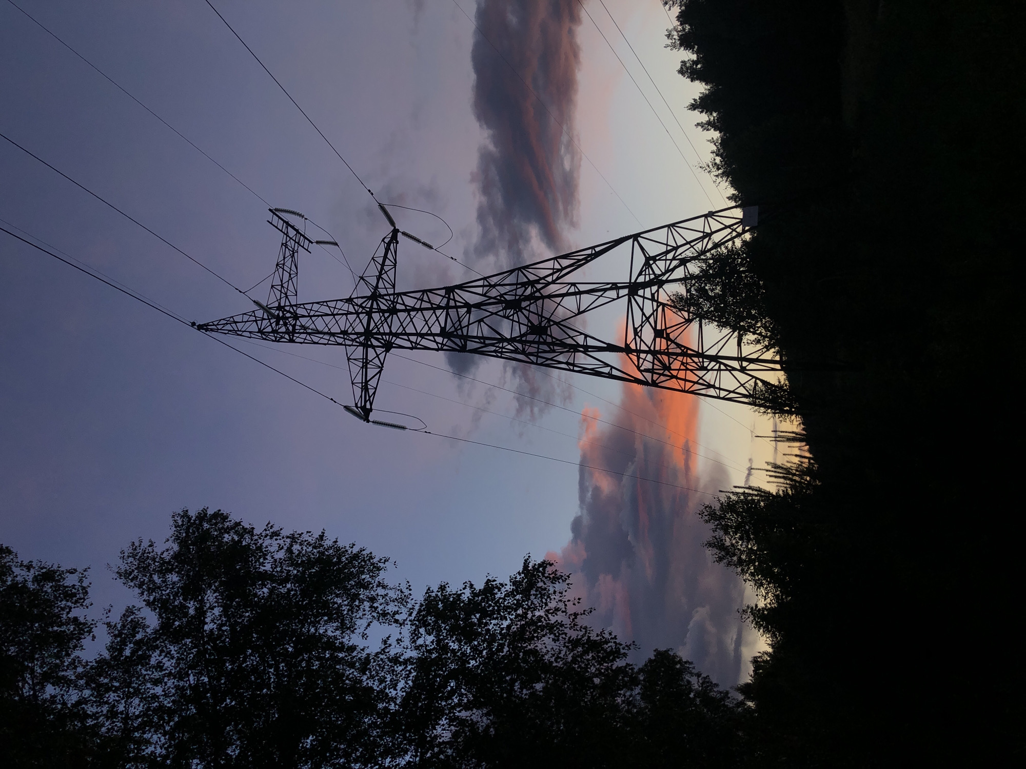 Transmission tower silhouetted against colorful twilight sky in Russia